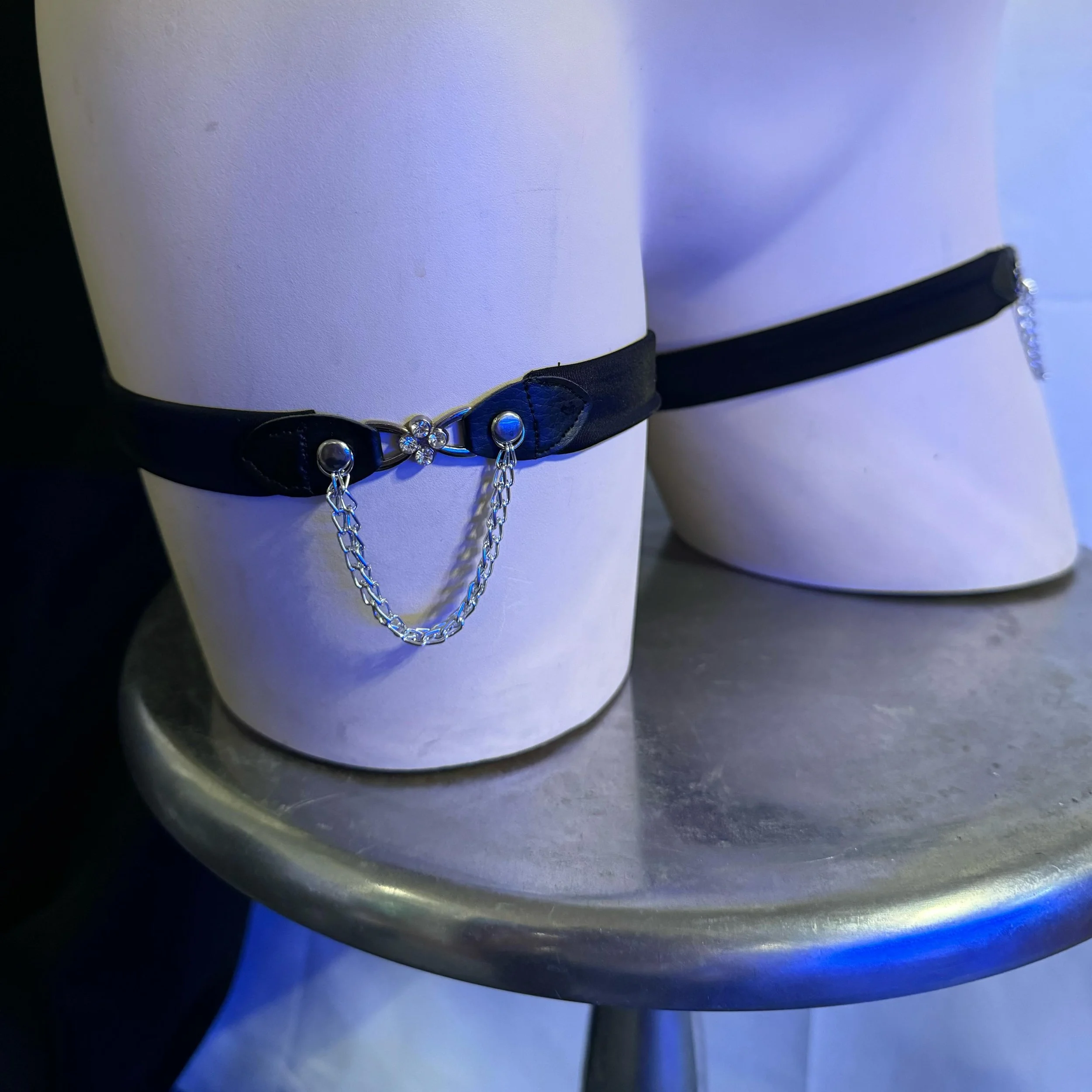 Mannequin leg with black garter and chain detail on silver stand