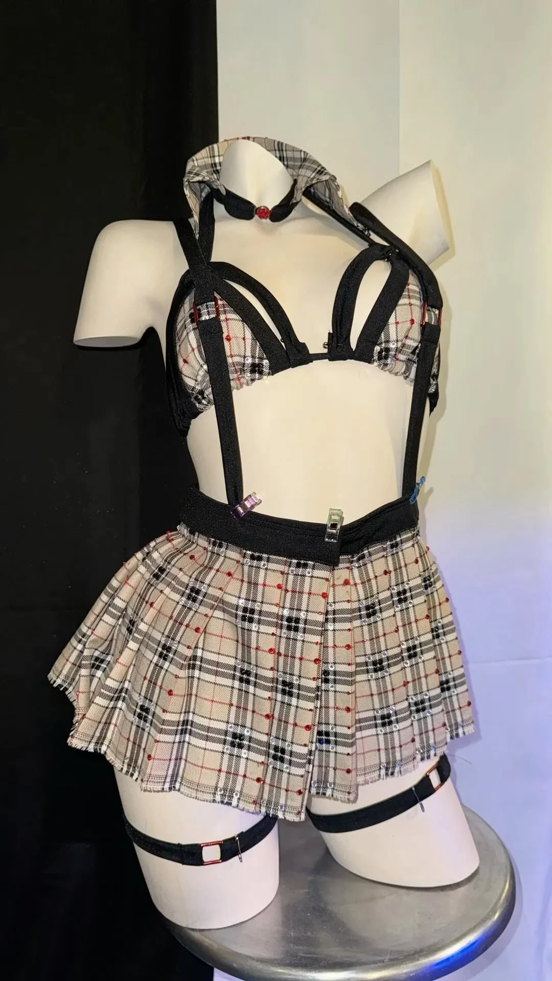 Mannequin wearing plaid lingerie set with harness and skirt on display.