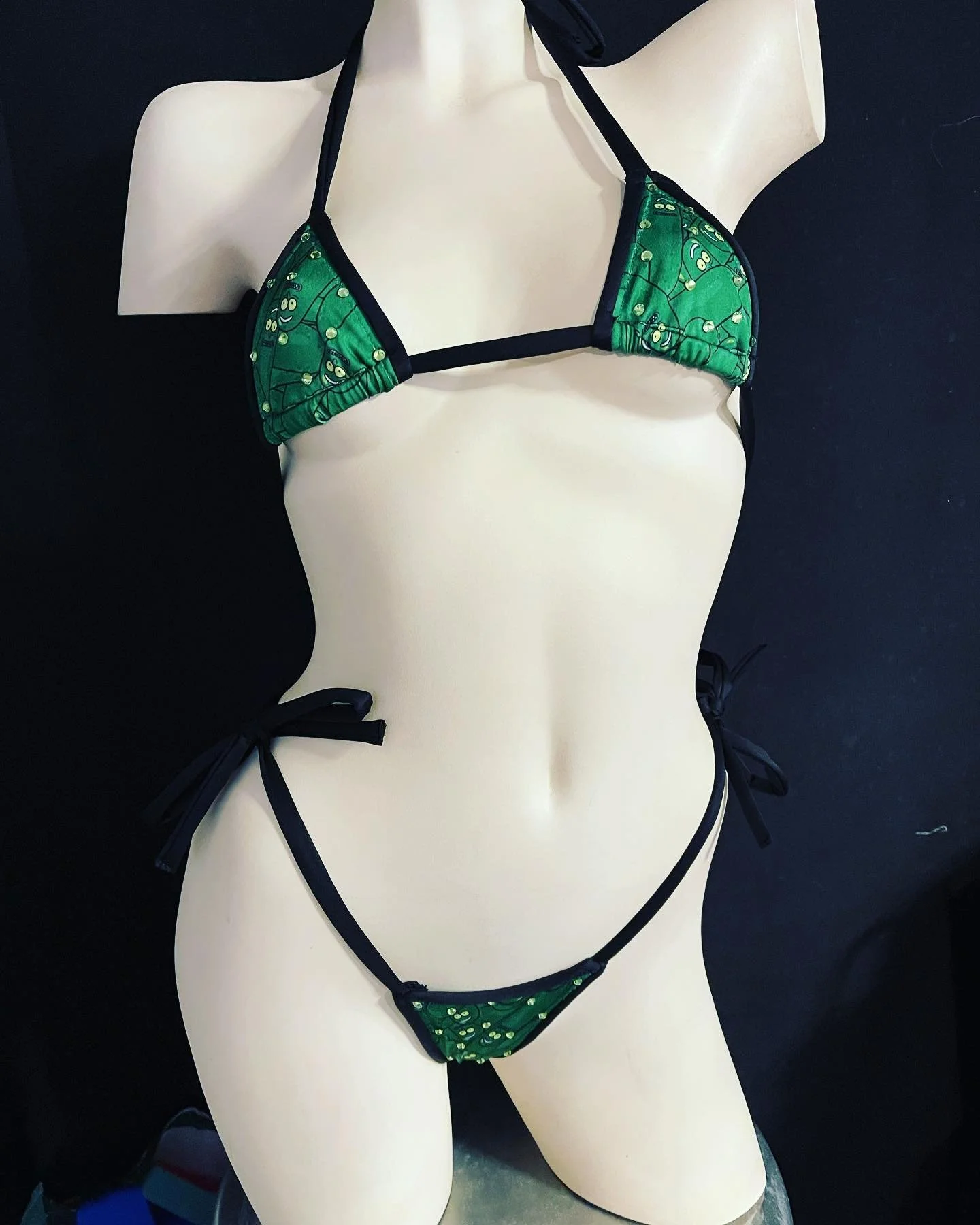 Mannequin wearing a green and black bikini against a dark background.