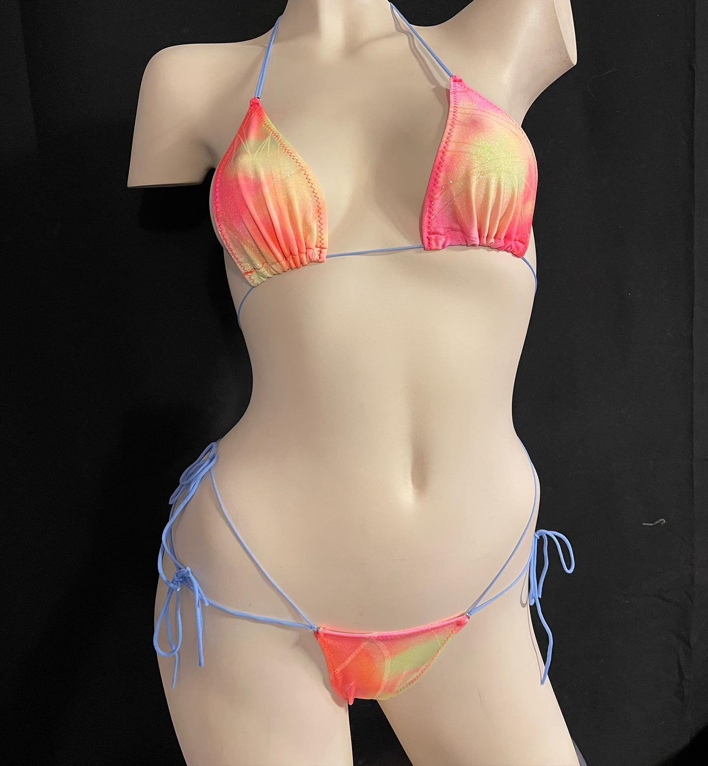 Mannequin displaying a colorful bikini with thin blue straps against a black background.