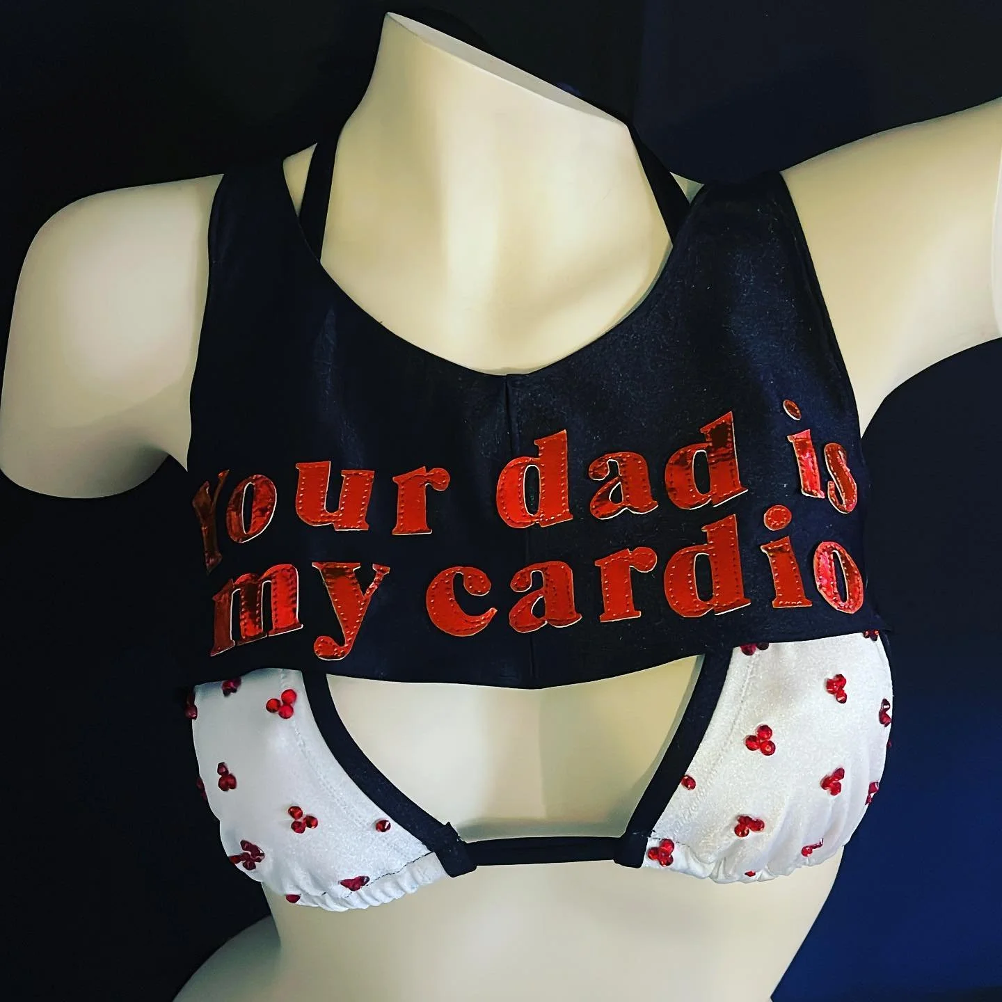 Mannequin wearing a black top with red text reading "Your dad is my cardio," paired with a white bikini bottom featuring red patterns.