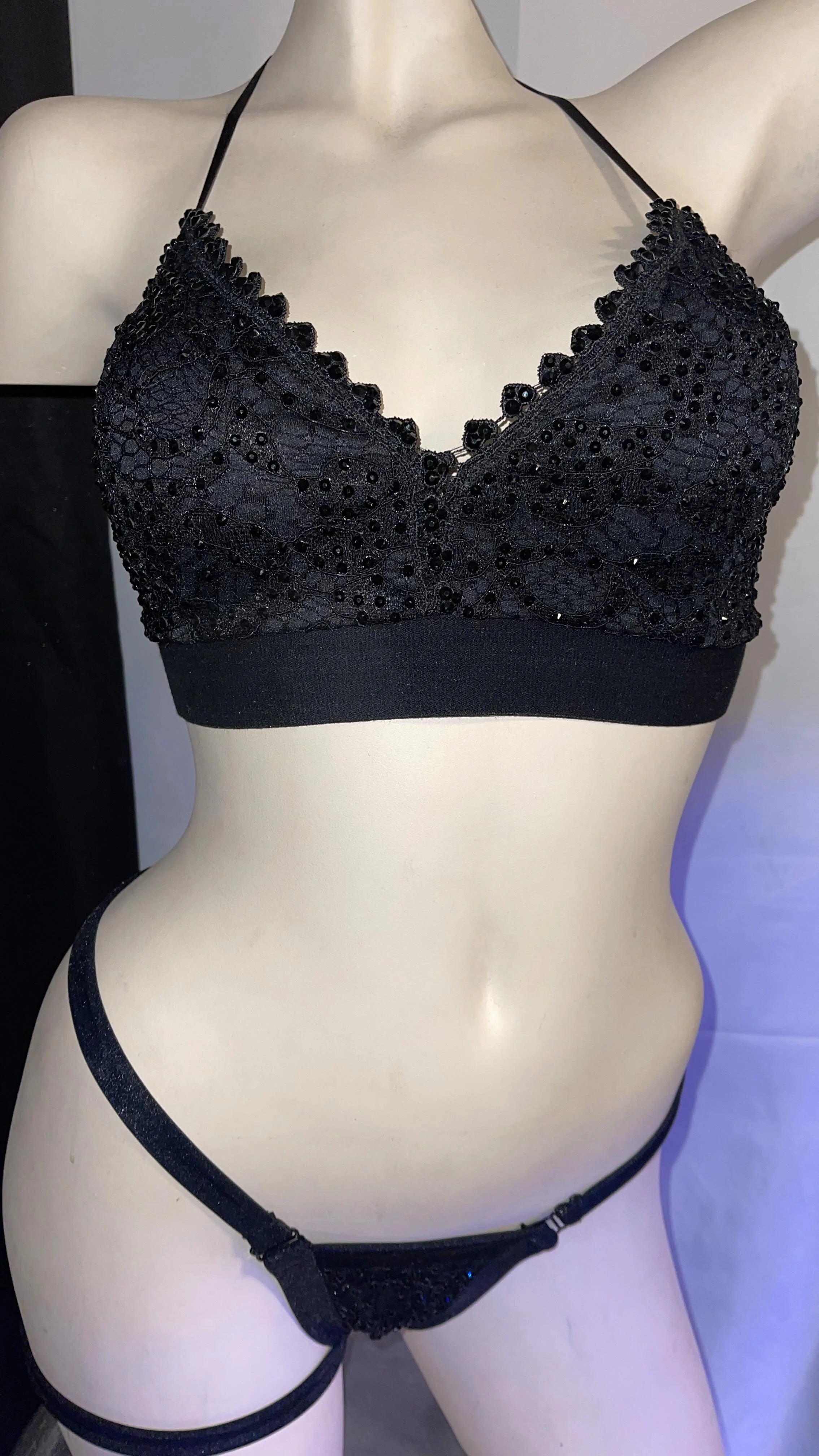 Mannequin wearing black lace bralette and matching panties with rhinestone details.