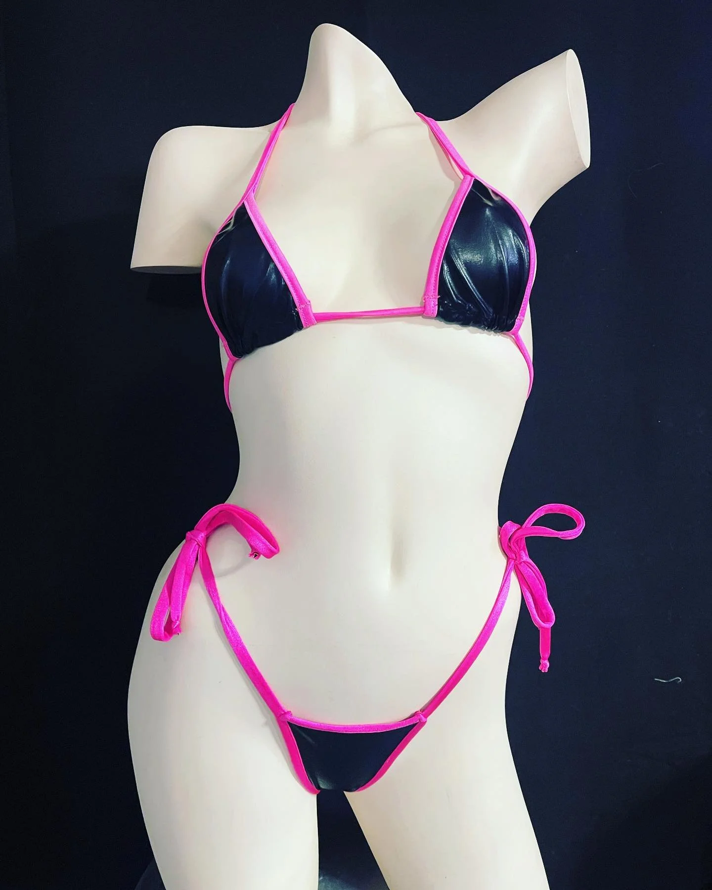 Black and pink bikini on a mannequin in front of a black background.