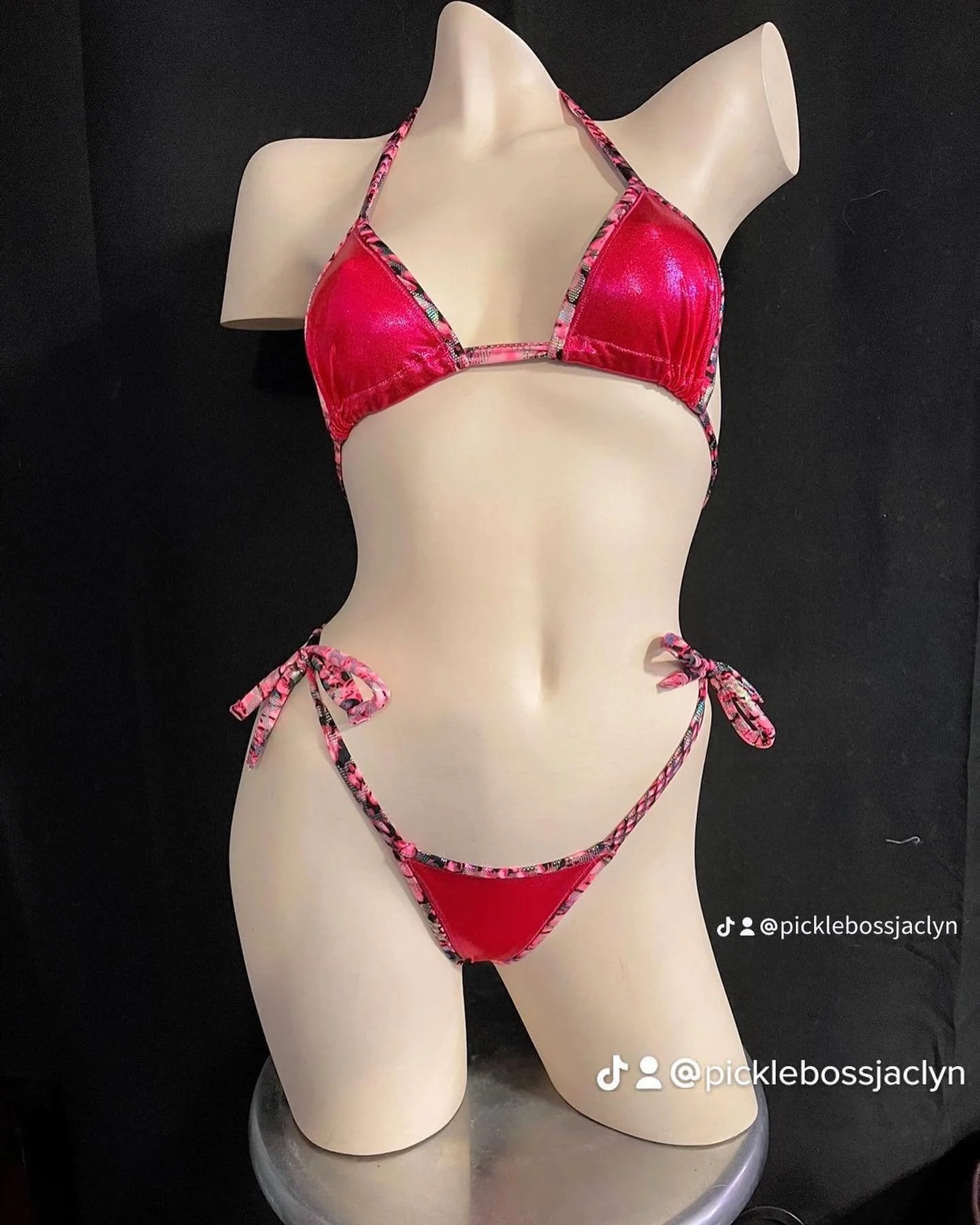 Mannequin wearing a red bikini with multicolored trim against a black background.