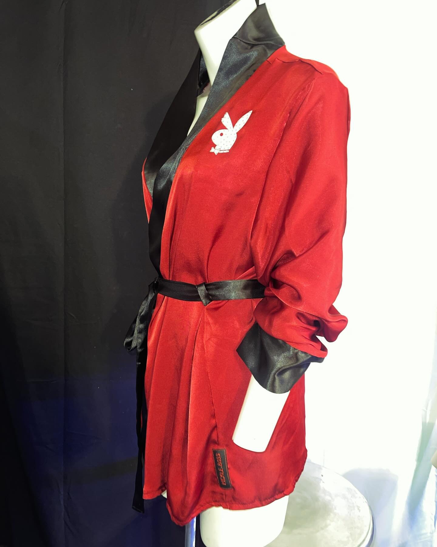 Red satin robe with black lapels and a white embroidered bunny logo on a mannequin.