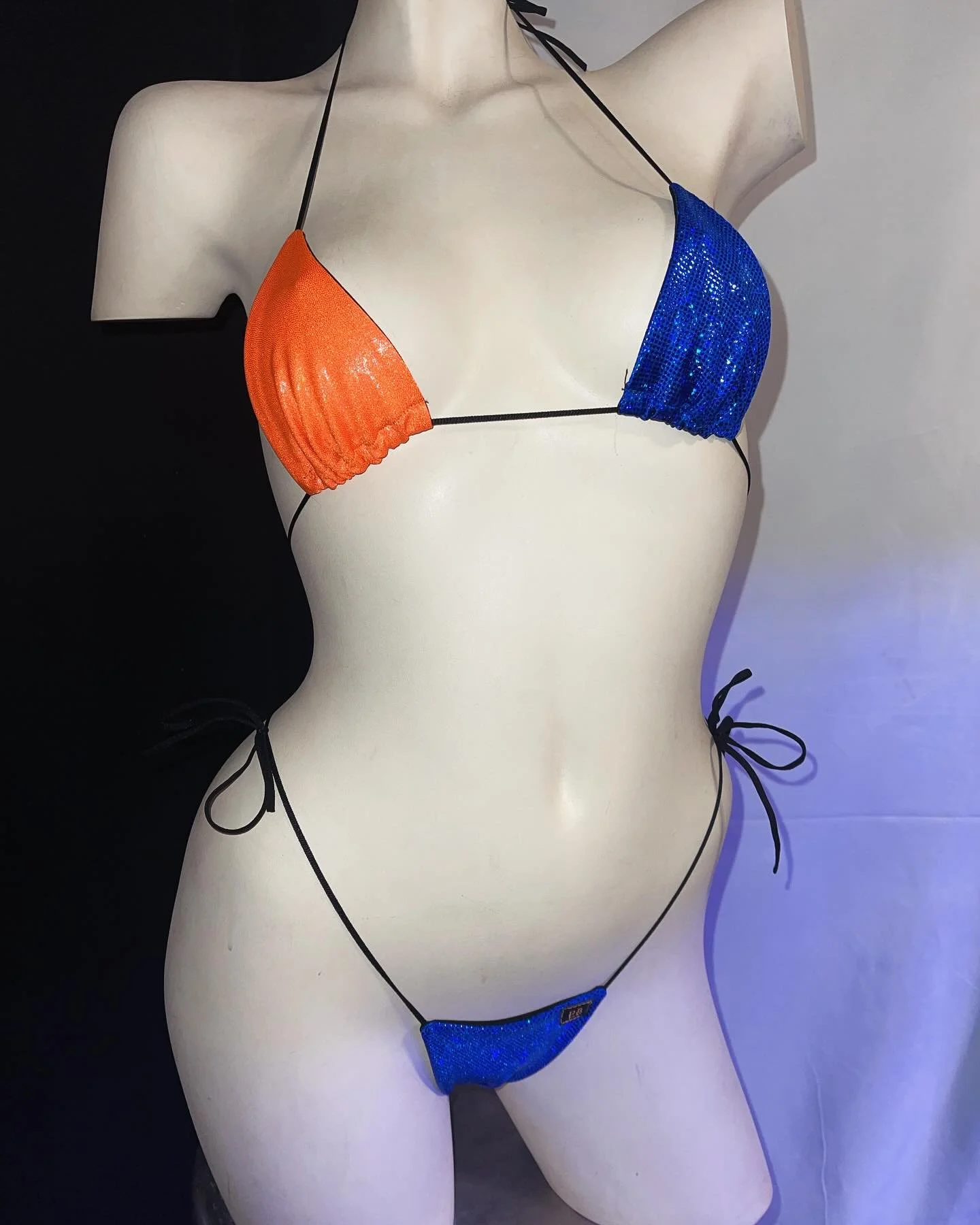 Mannequin wearing an orange and blue sequin bikini with black straps.