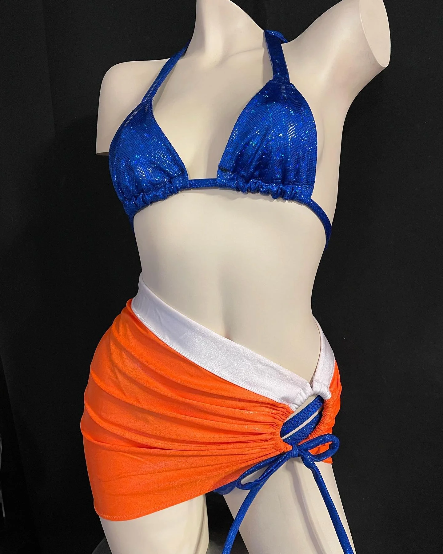 Mannequin wearing a blue bikini top and orange sarong skirt.