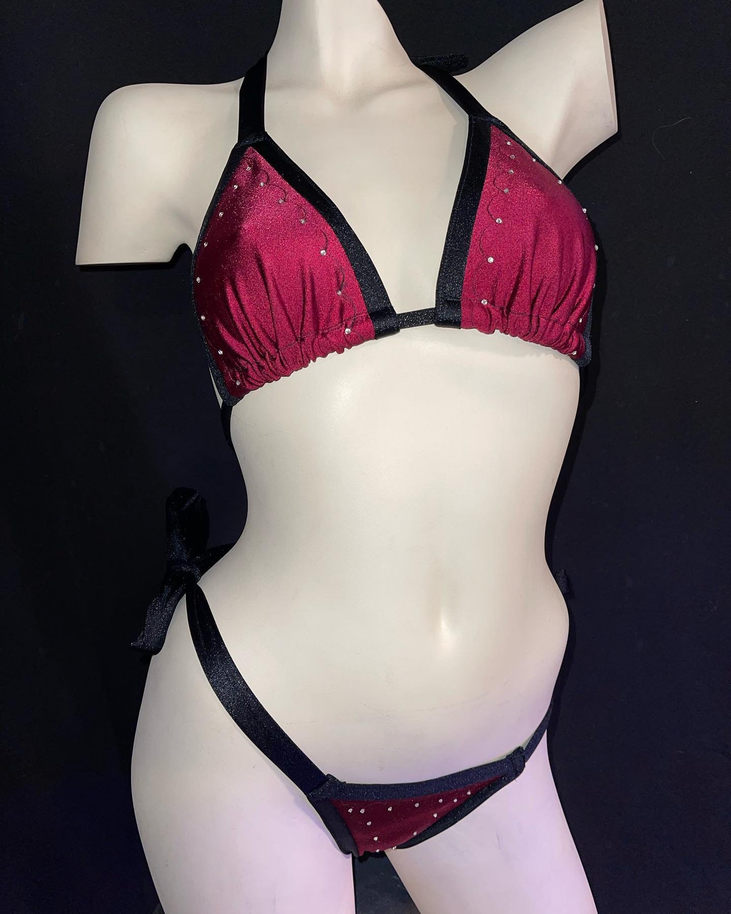 Mannequin wearing a burgundy bikini with black trim and rhinestone embellishments.