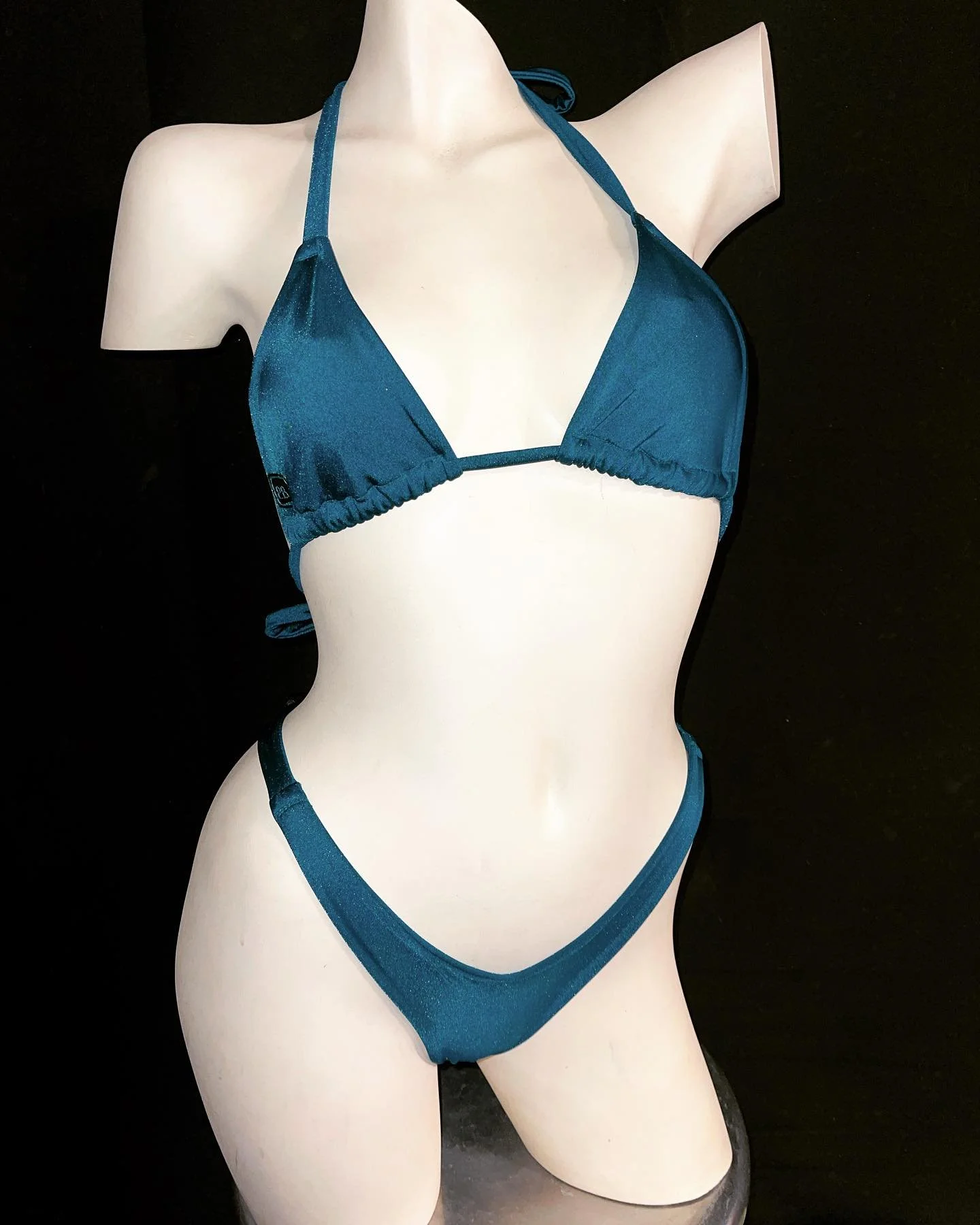 Mannequin wearing a blue bikini against a black background.