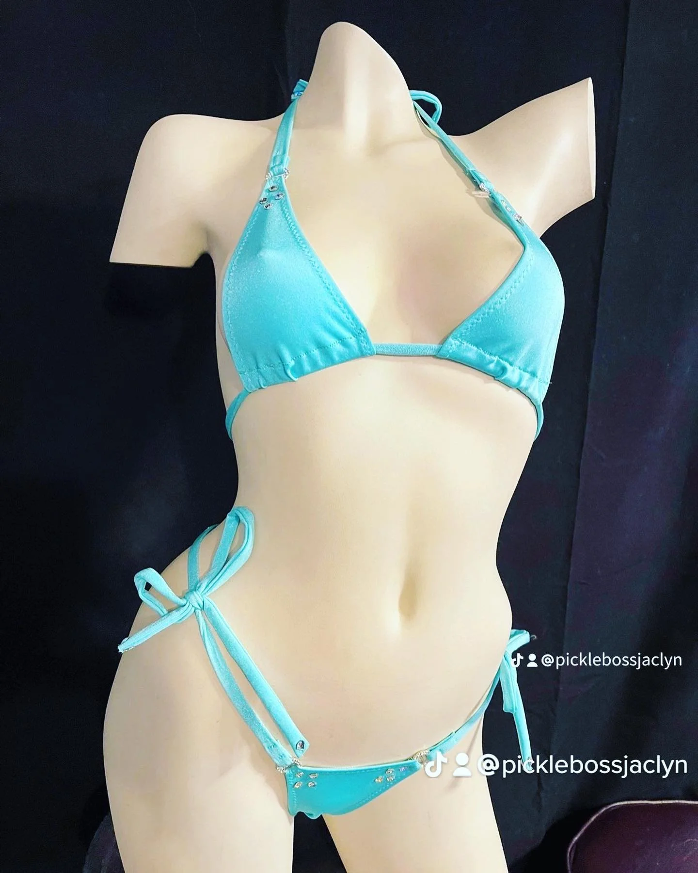 Mannequin wearing a blue bikini against a dark background.