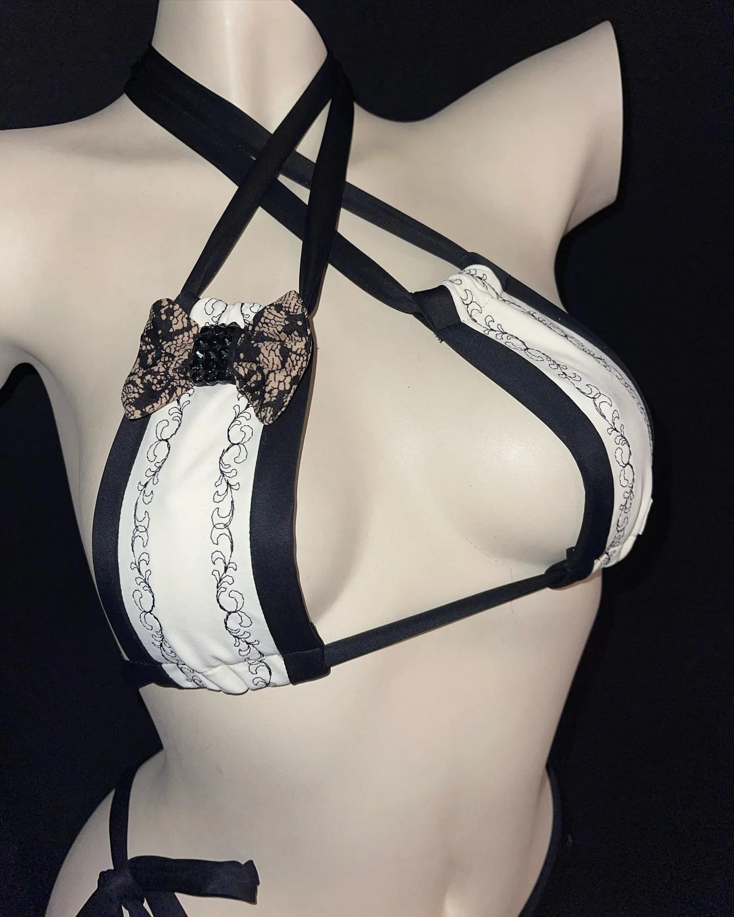 A mannequin wearing a black and white strappy bikini top with a decorative bow at the front.