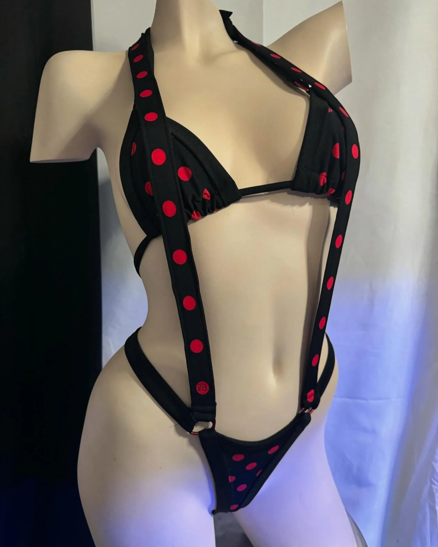 Mannequin wearing black polka dot bikini with red dots and suspenders.