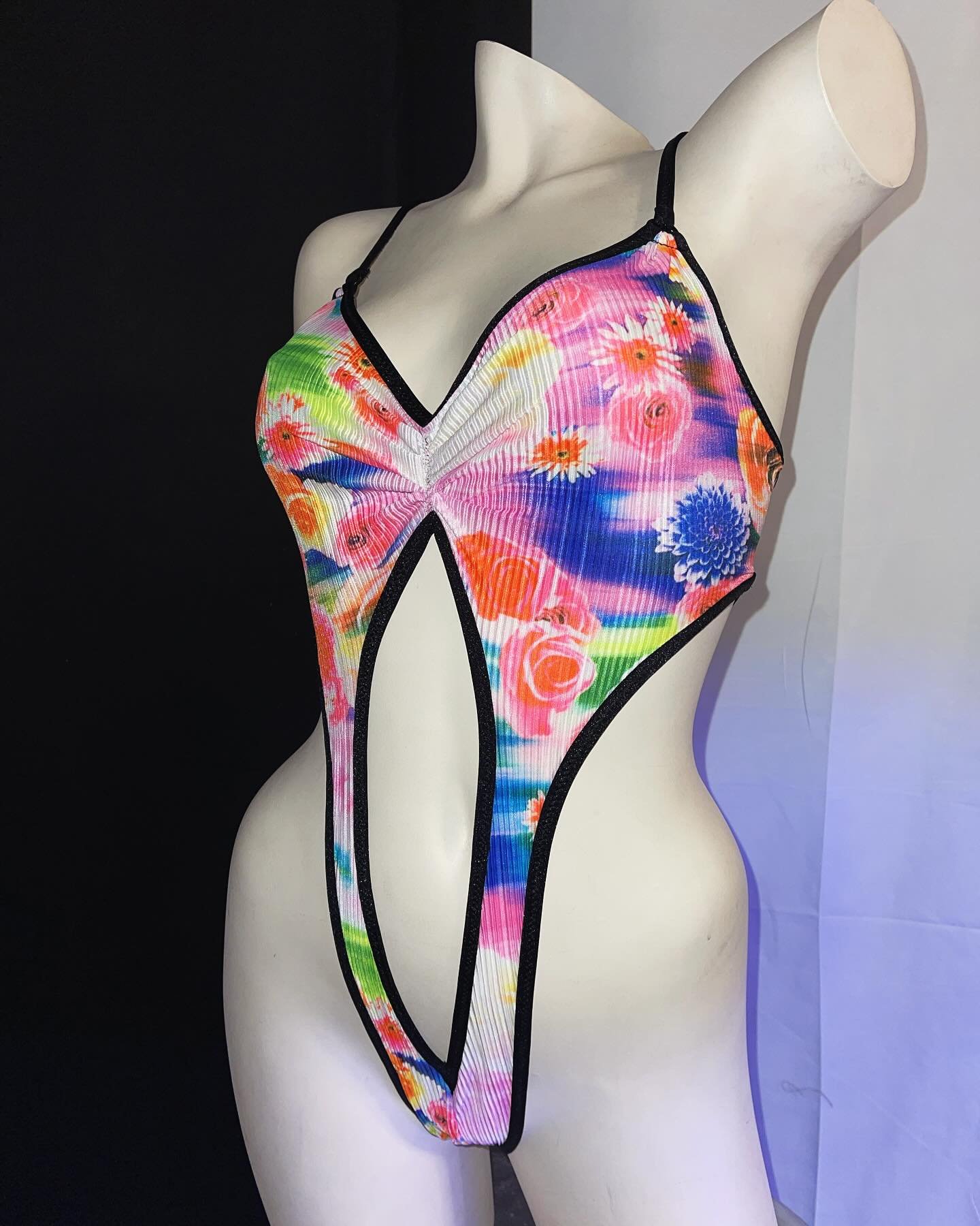 Mannequin wearing a colorful floral swimsuit under bright lighting.
