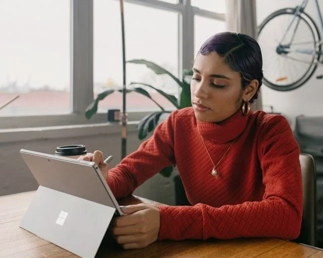 Latina woman with orange turtleneck on a computer
