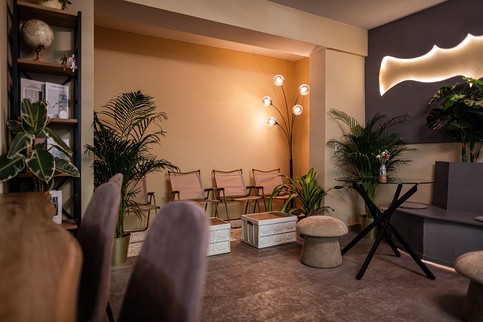 Gemütliche Wartebereich mit Stühlen, Pflanzen, Stehlampe und moderner Wanddeko.