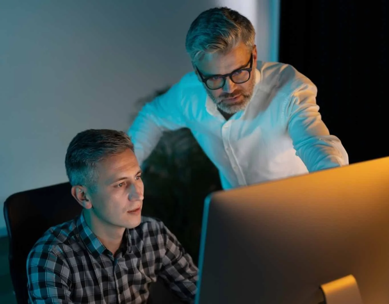 Two men working intently in front of a computer