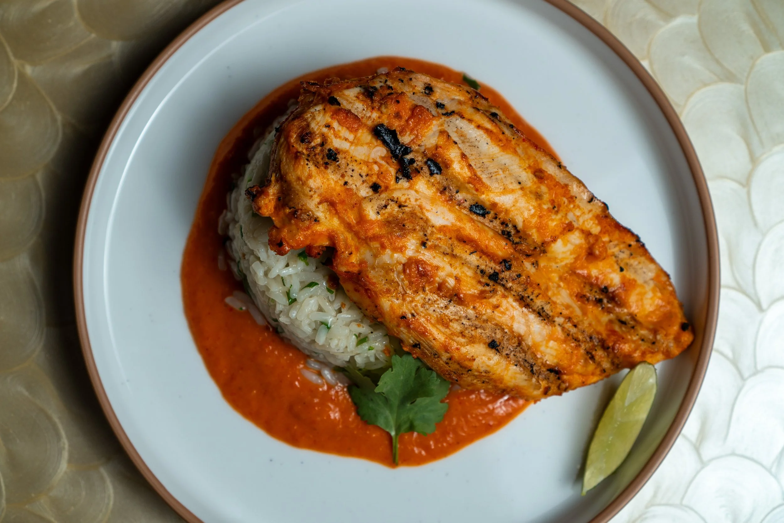 Mojo rojo chicken with rice and sauce on a ceramic plate.