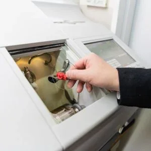 Person using a tool to insert or remove an item from a top-loading washing machine