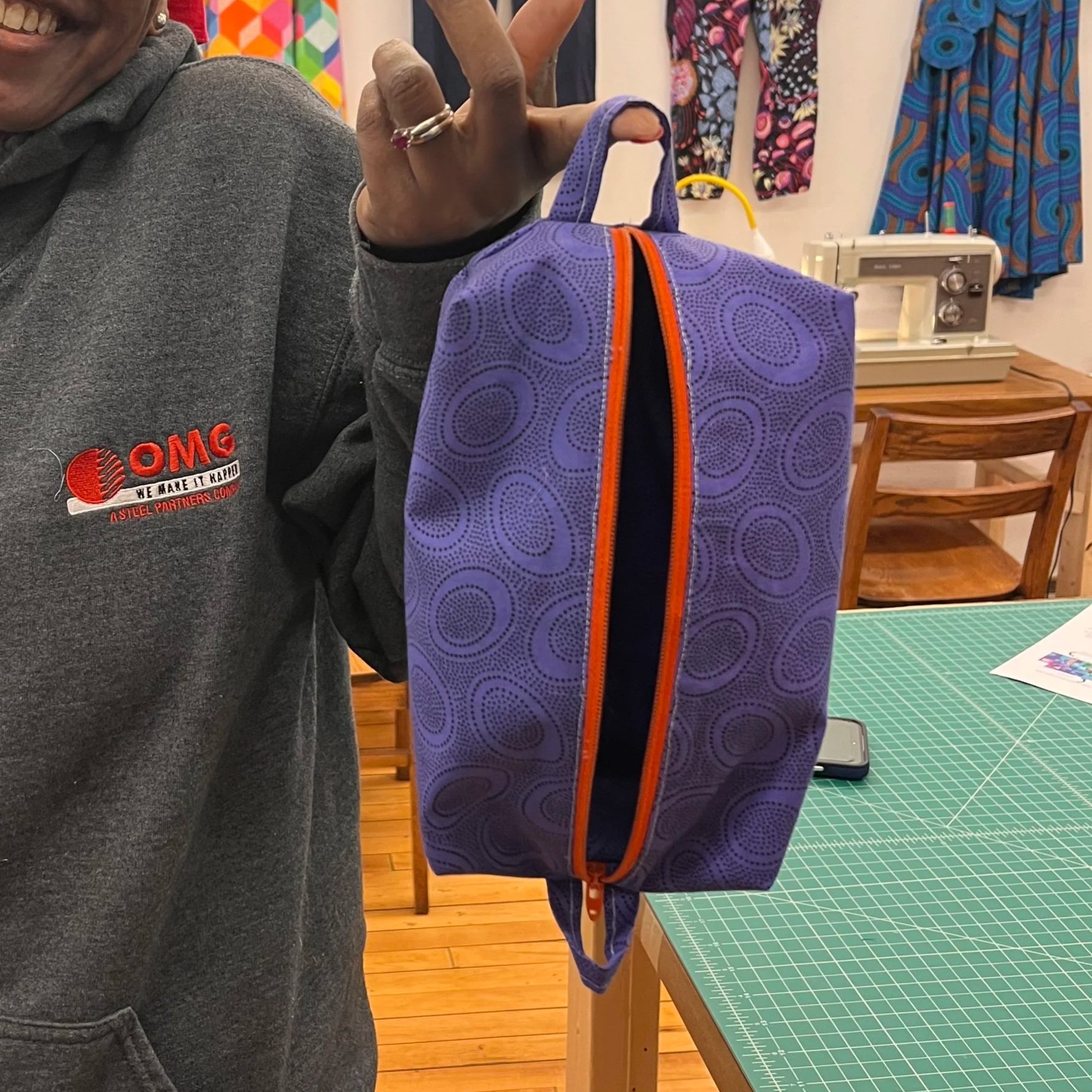 Student holding completed a purple bag with orange zipper bag made in sewing class in Northampton MA.