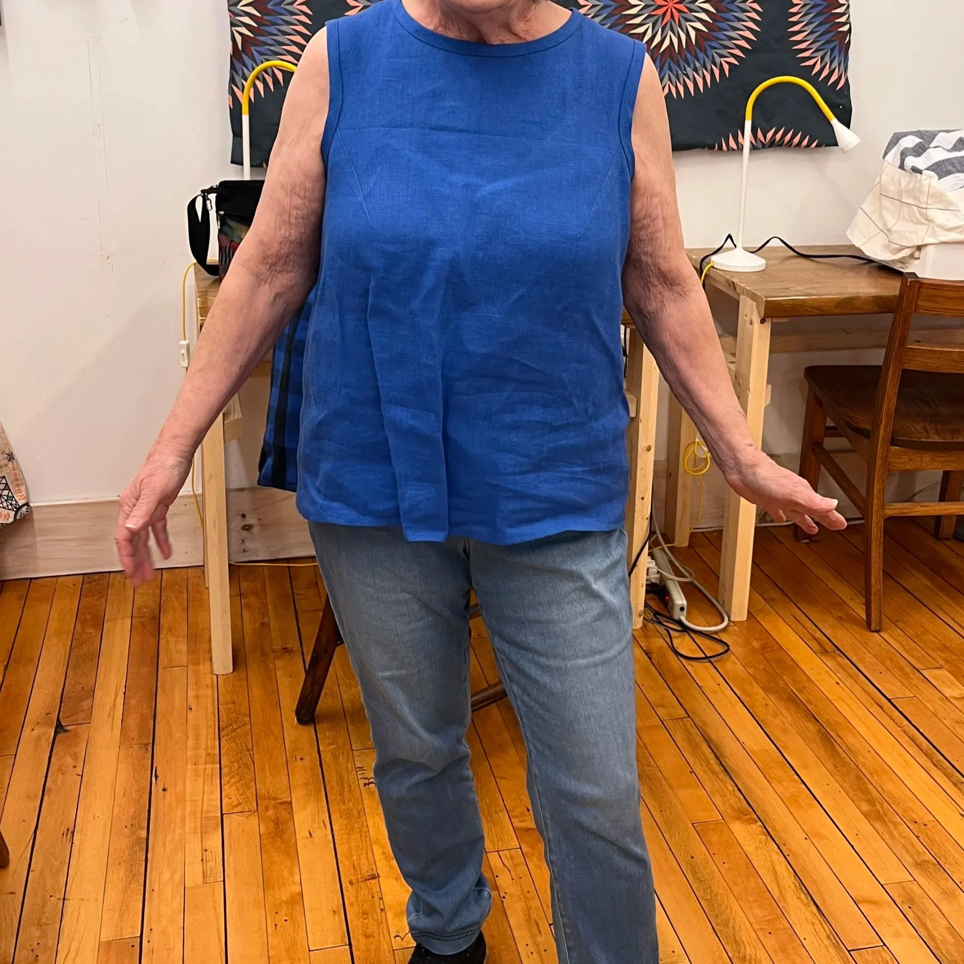 A student wearing a sleeveless blue linen shirt made in sewing, mending, altering class.