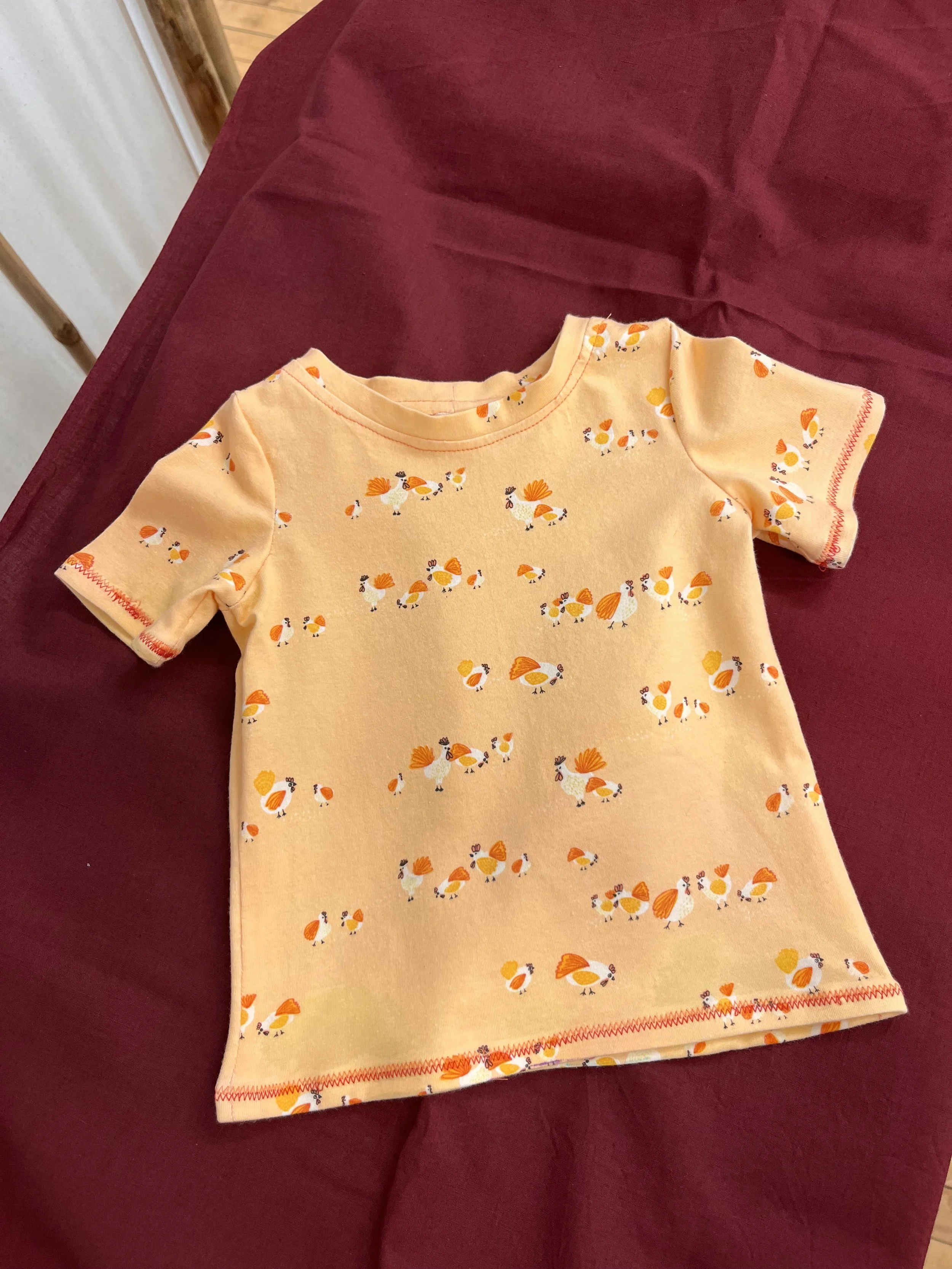 Baby shirt made in beginning sewing class with orange jersey fabric