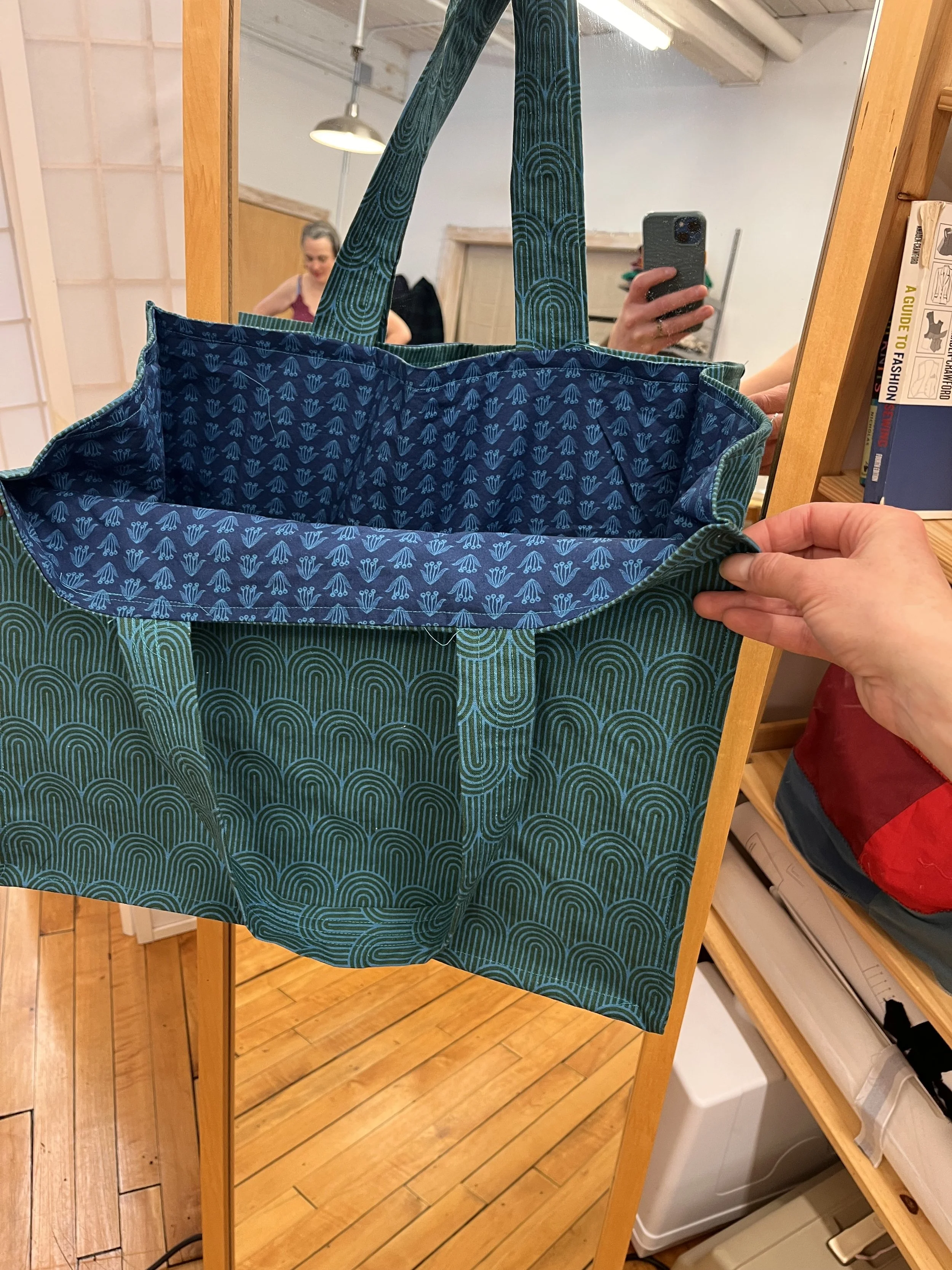 An open teal reusable shopping bag with a patterned interior, made in sewing class in Florence Ma