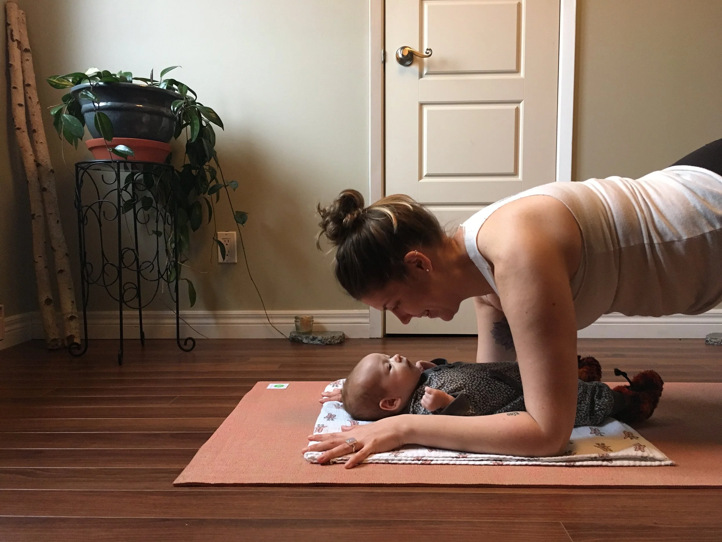 A person doing yoga with a baby on a pink yoga mat