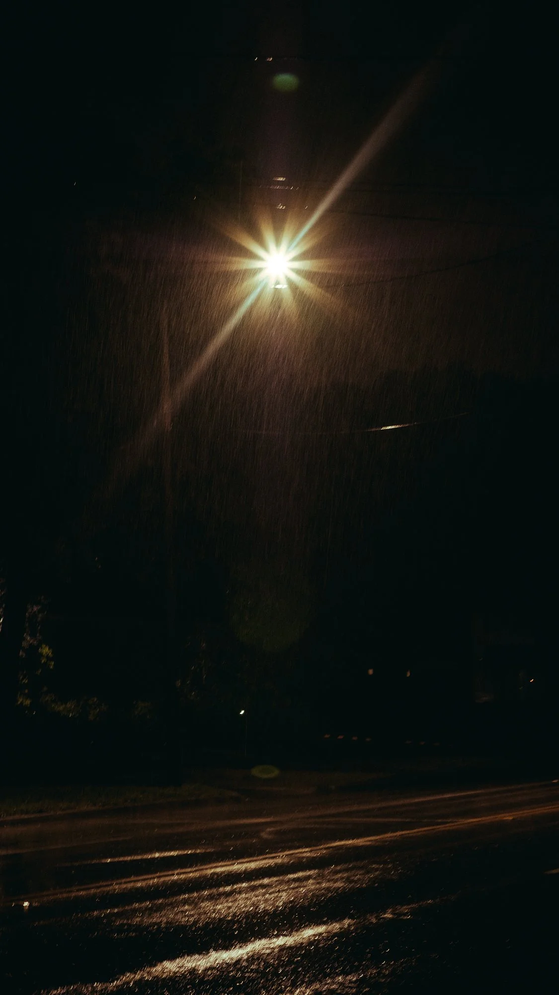 Bright streetlight illuminating a wet road at night with visible rain falling taken in Dallas TExasa