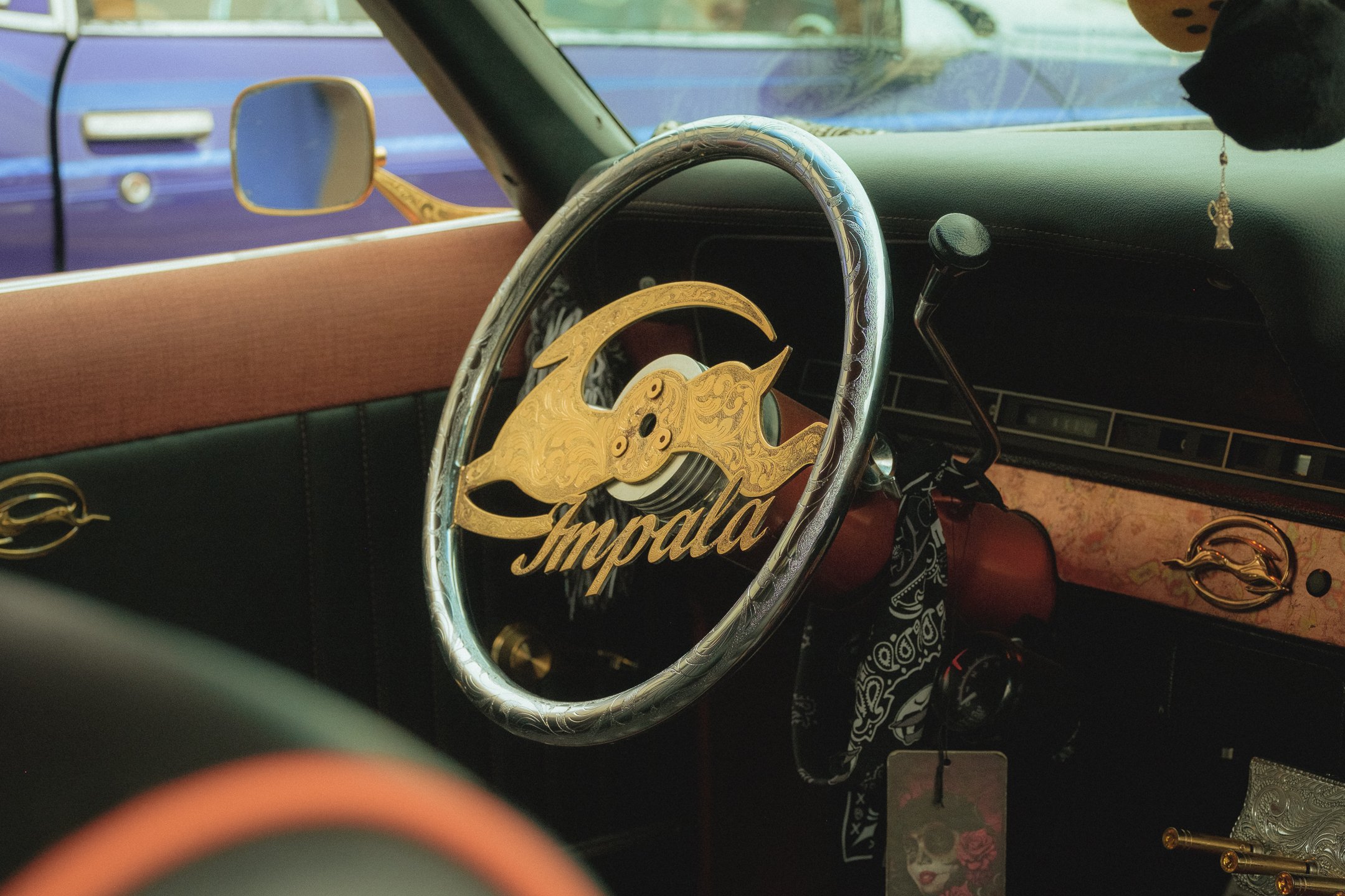 Interior of a vintage car with a custom steering wheel that has a gold Impala logo Photographed in Dallas Texas