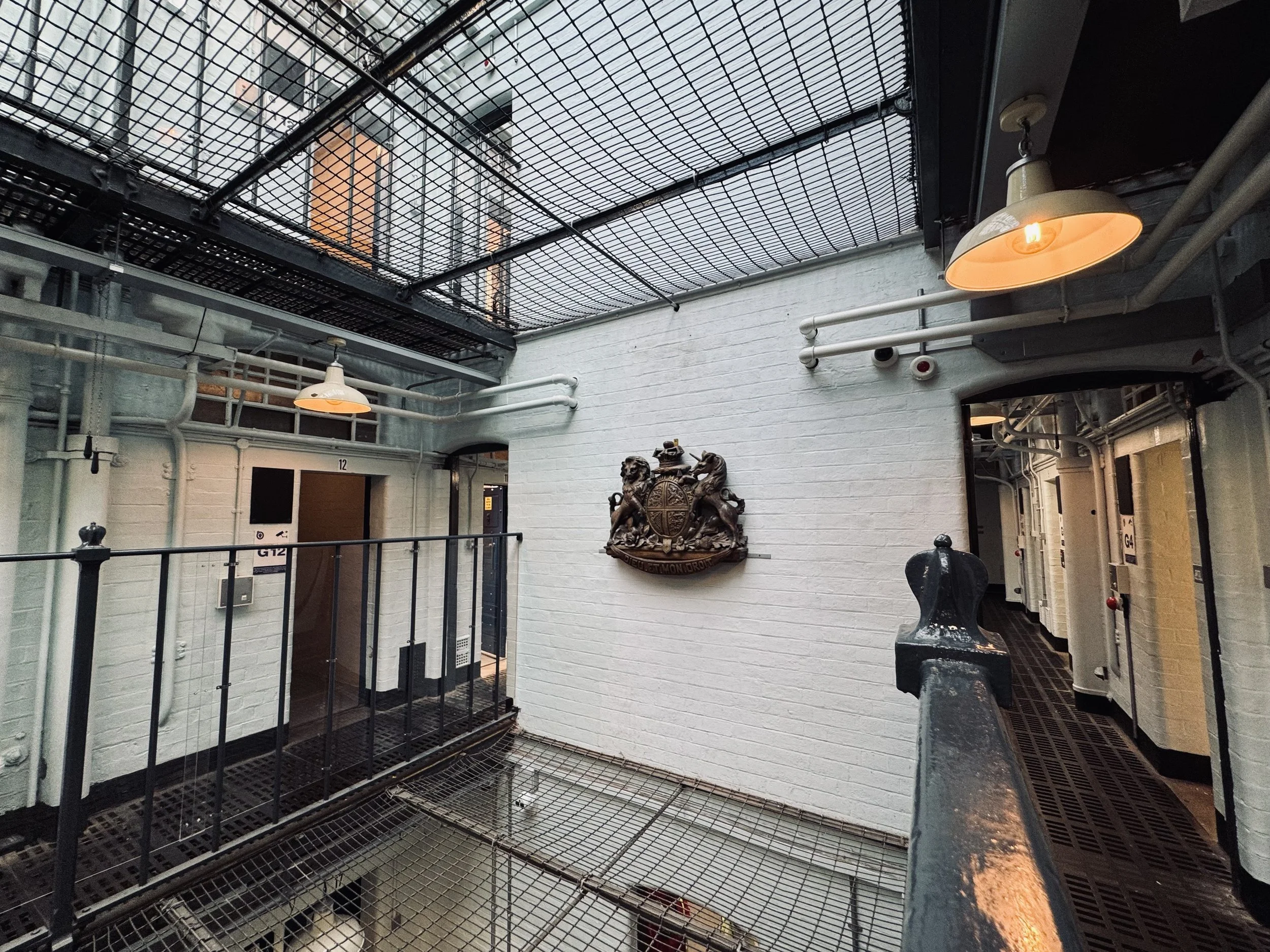 Interior view of an industrial-style building with metal walkways, white brick walls, a crest on the wall, and vintage lighting.