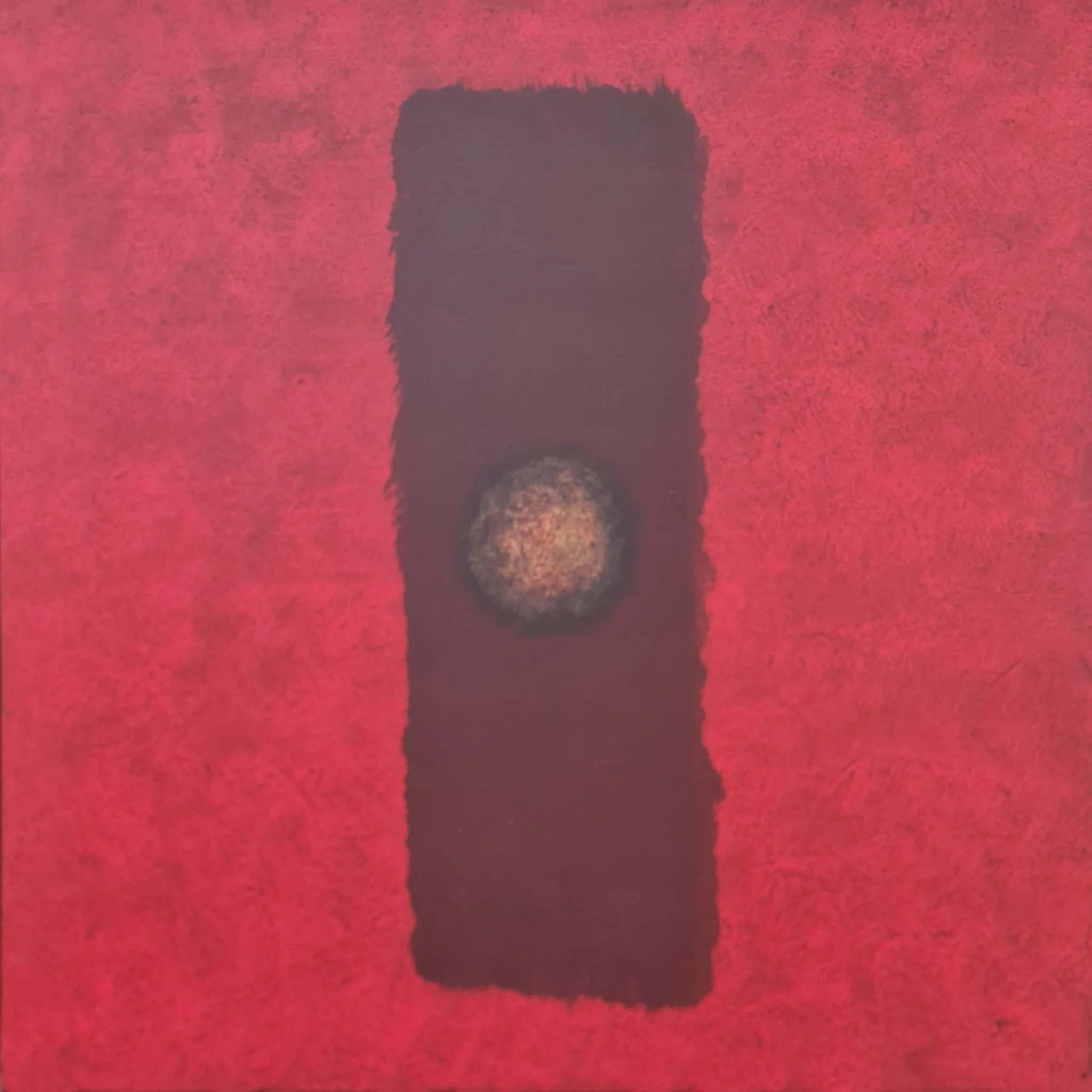 A textured red background with a black rectangular shape in the center, featuring a circular, grainy, light-colored area in the middle of the rectangle.