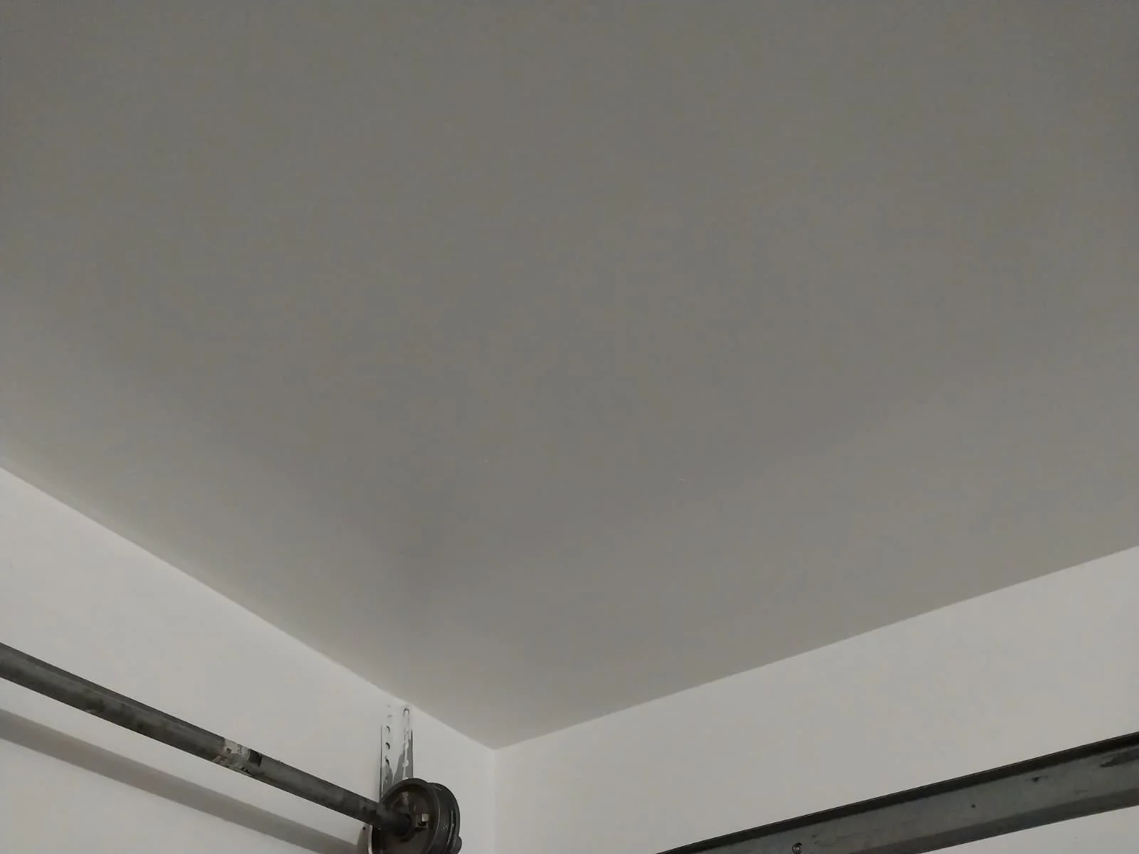 Ceiling with exposed garage door rails and hardware.