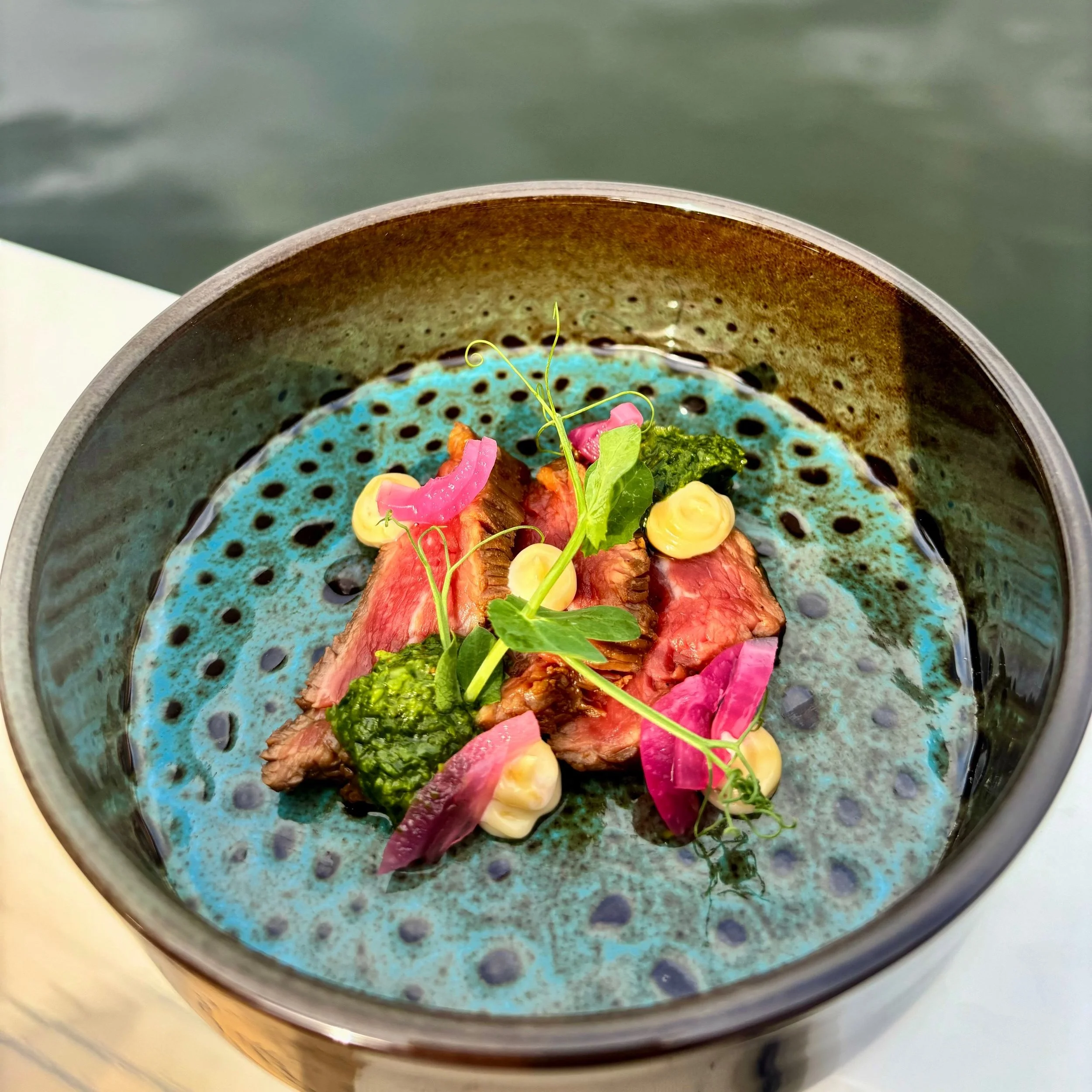 Verschillende soorten tomaten op een metalen plaat, inclusief grote heirloom en kleinere cherrytomaten in verschillende kleuren zoals rood, oranje, en groen.