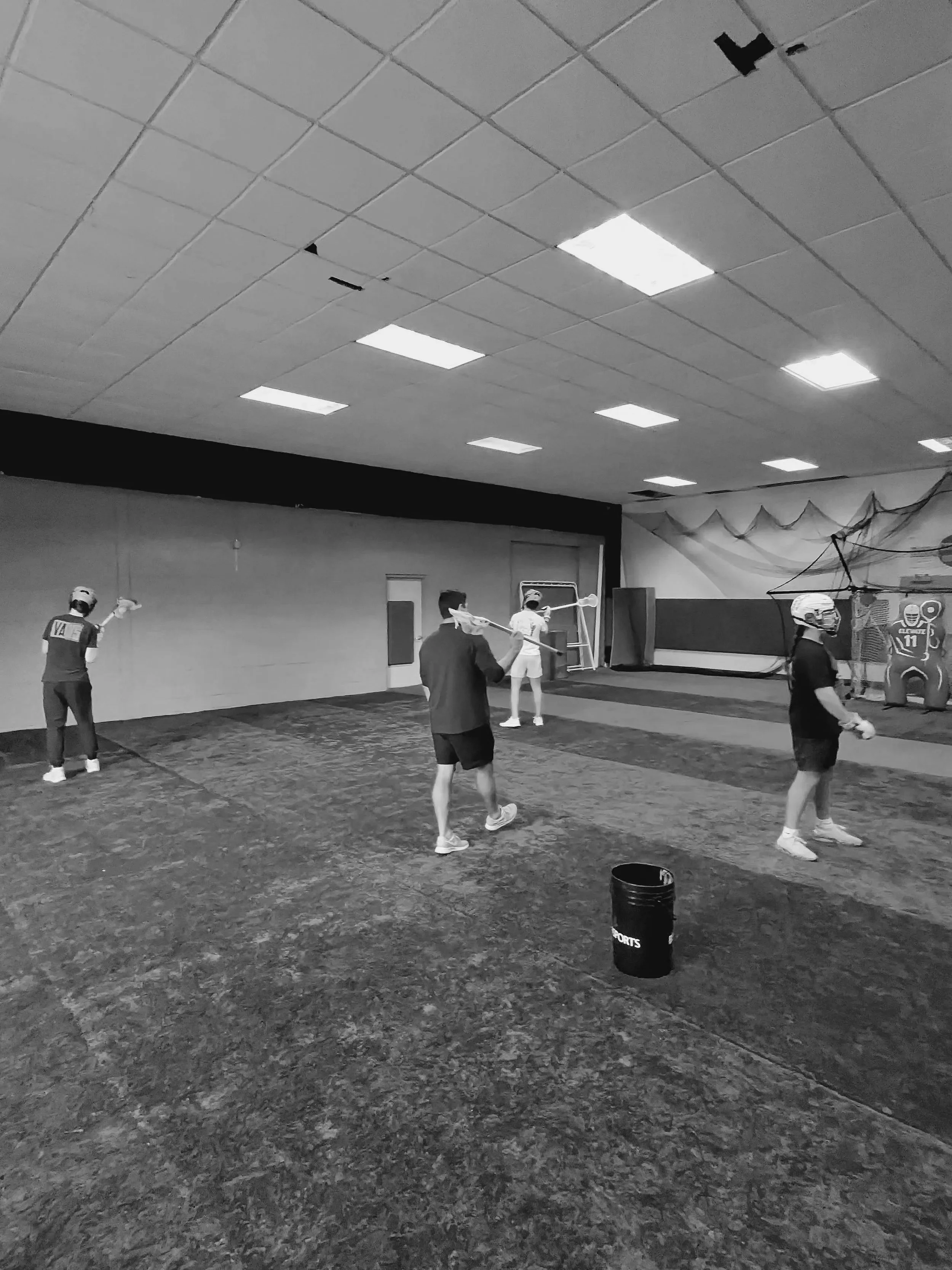 People practicing floorball in an indoor gym.