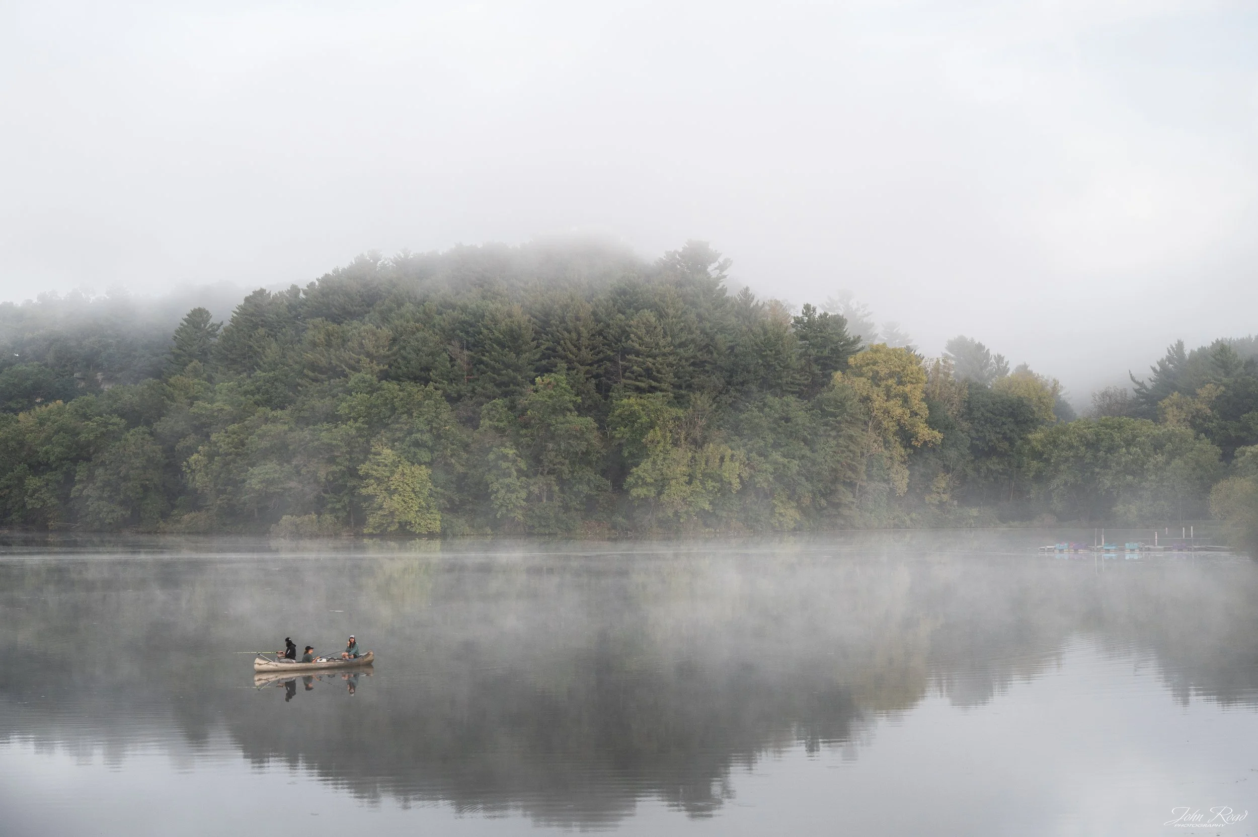 Canoe drifting through soft morning mist on a calm lake at Governor Dodge State Park, Wisconsin, photographed by John Road.