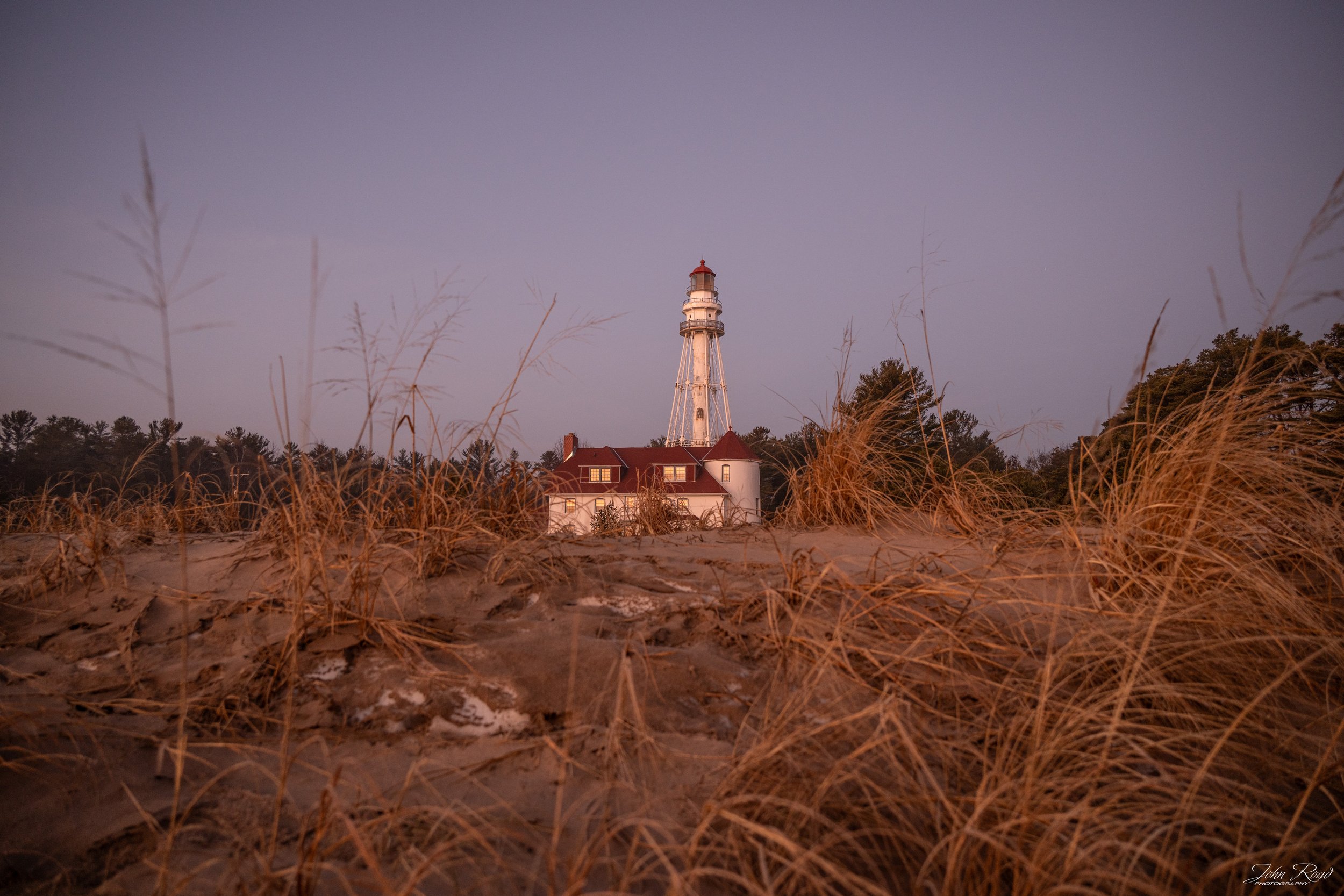 A Quiet Distance” landscape photo by John Road, featuring a calm lakeshore at sunrise, soft pastel sky, and distant horizon. Available for prints on metal, canvas, and luster paper.