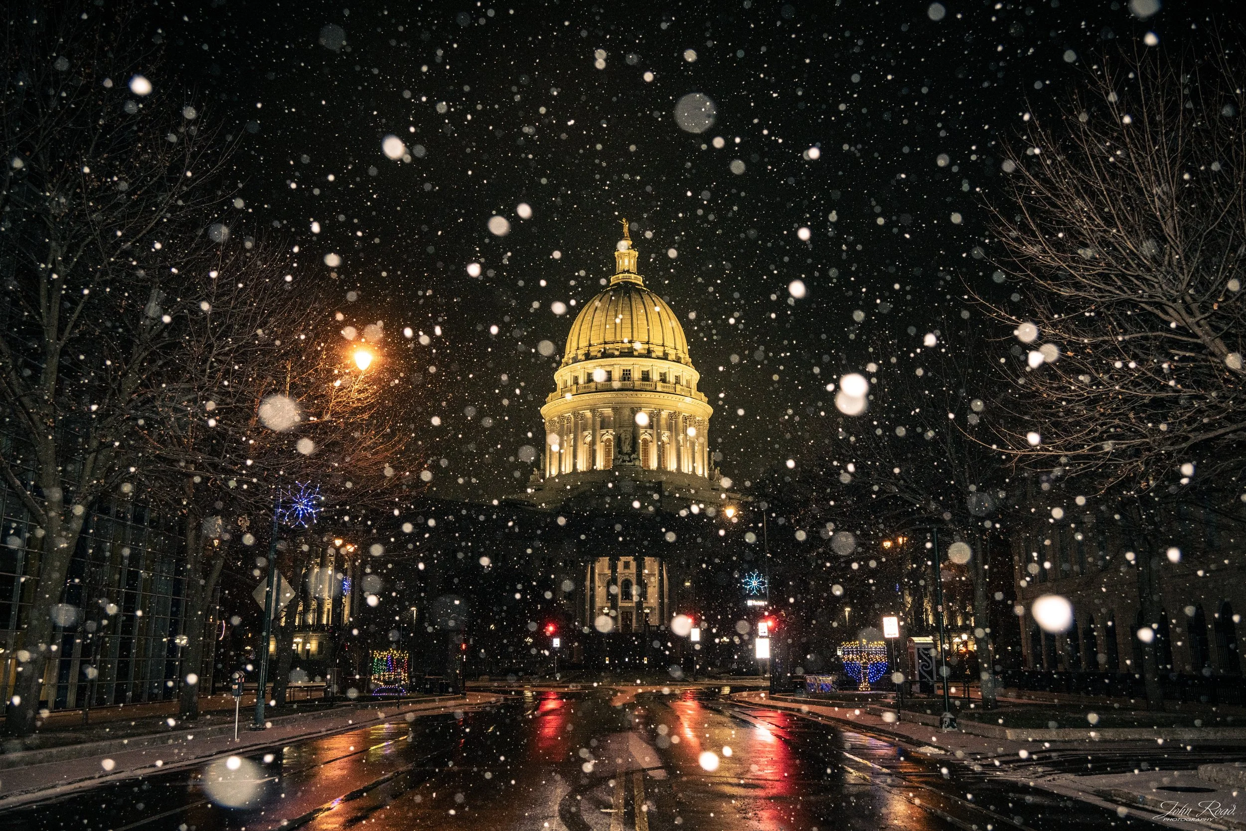 Snowfall illuminated by streetlights in front of the Wisconsin State Capitol at night, photographed by John Road.