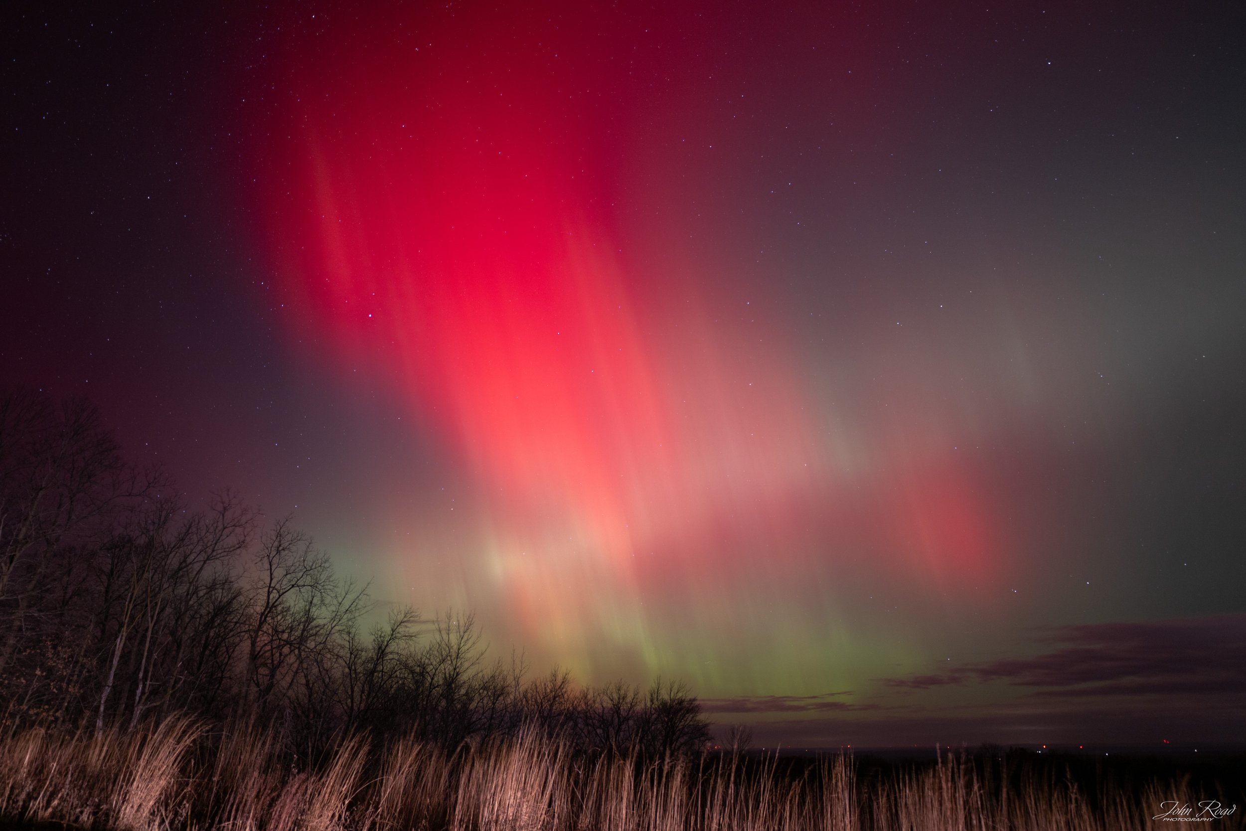 Vivid red and green aurora lights over Wisconsin horizon, fine art landscape photograph by John Road.