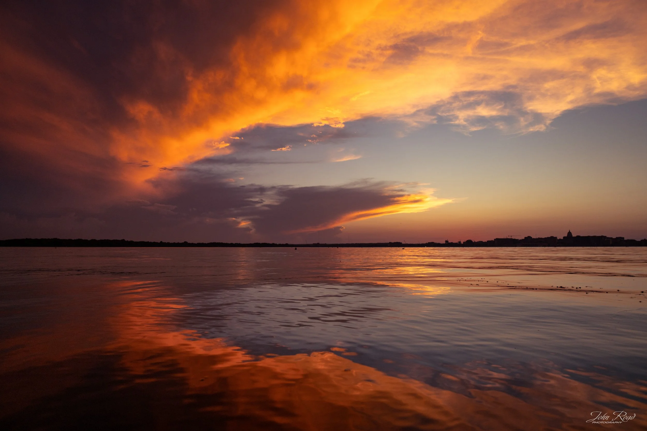 Dramatic orange sunset reflected across calm lake water