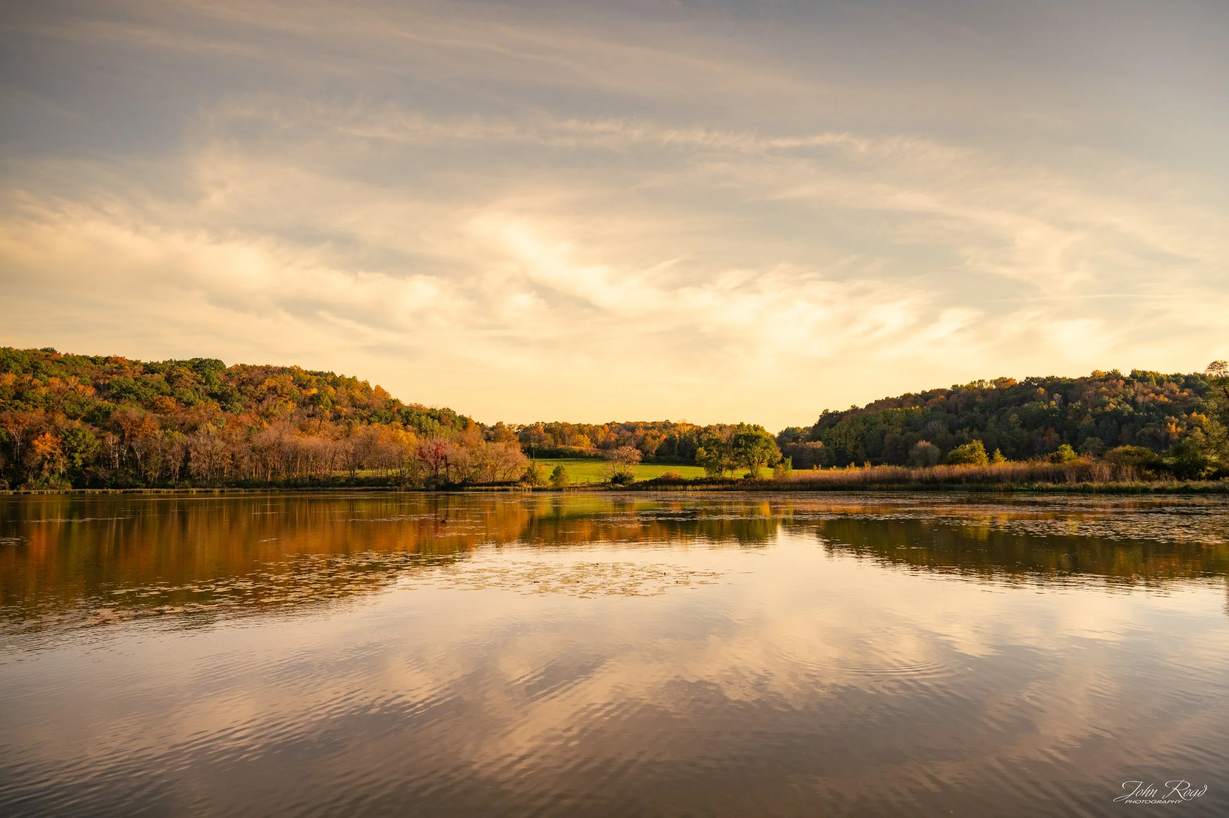 Golden autumn trees reflected in the calm water of Indian Lake, Wisconsin, surrounded by colorful fall foliage.