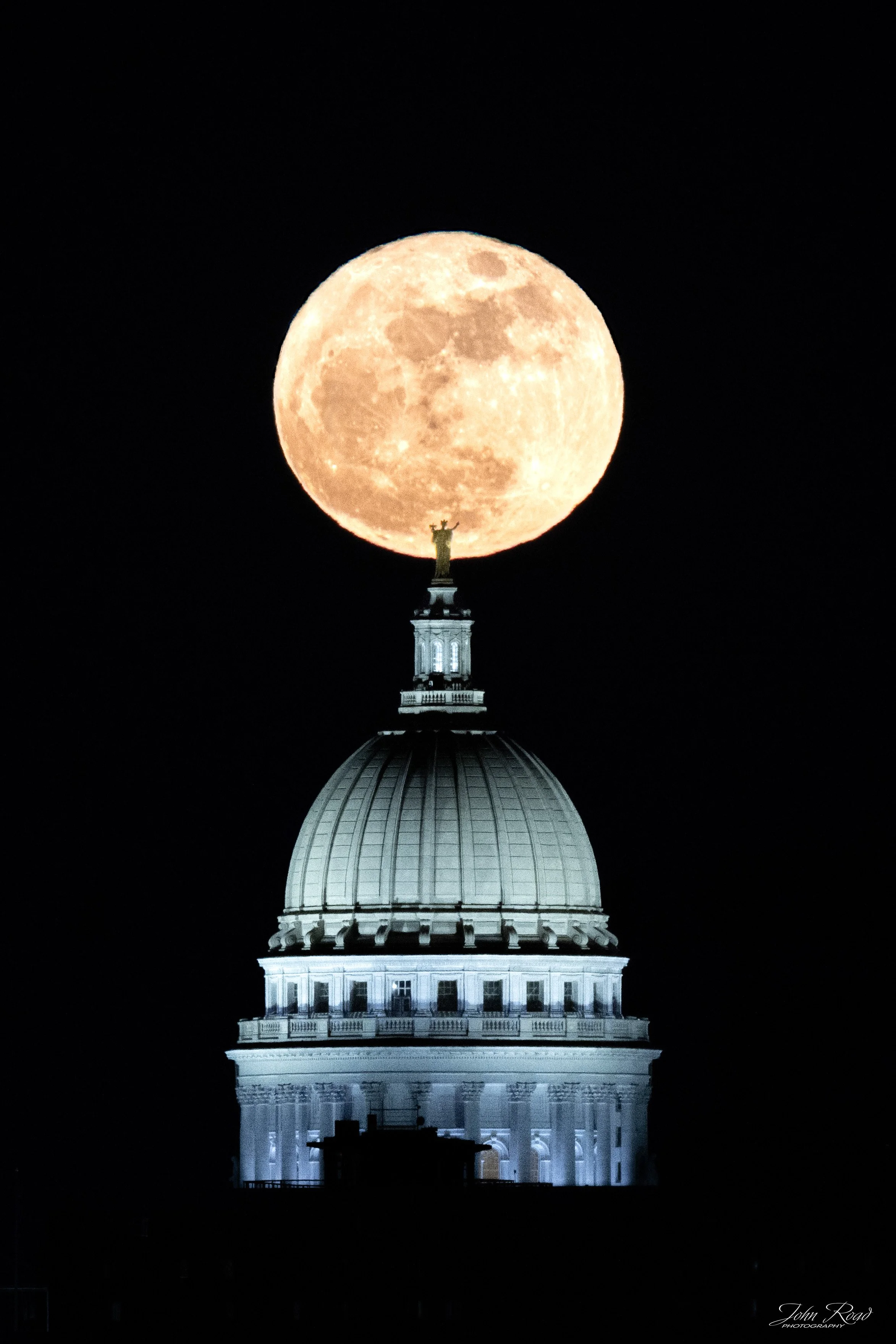 A precise alignment between the moon and the Capitol dome creates a visually balanced composition. The clean, dark background emphasizes form and contrast, turning a fleeting moment into a study of timing, symmetry, and quiet tension.