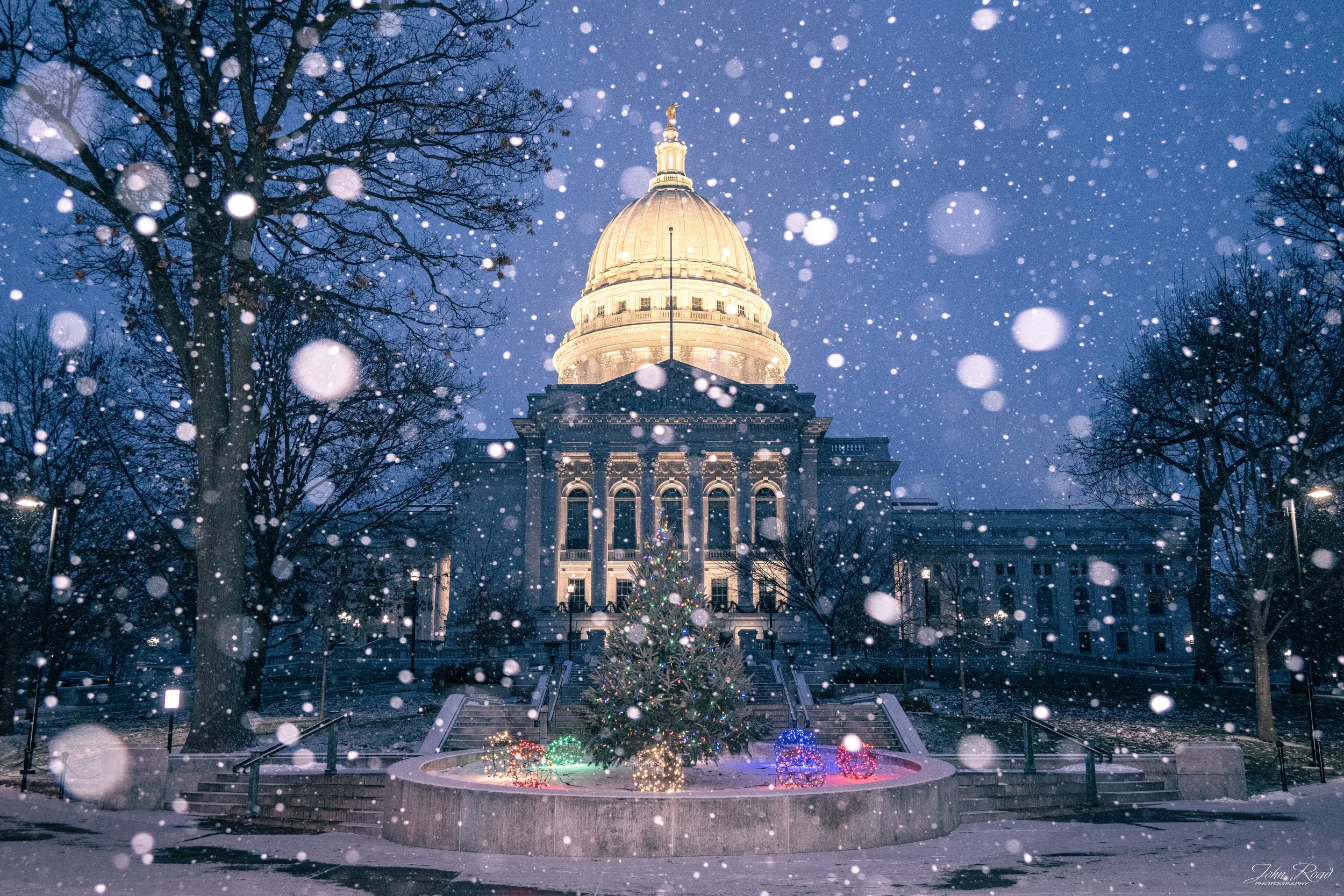Wisconsin State Capitol with Christmas tree during heavy snowfall at dawn, photographed by John Road.