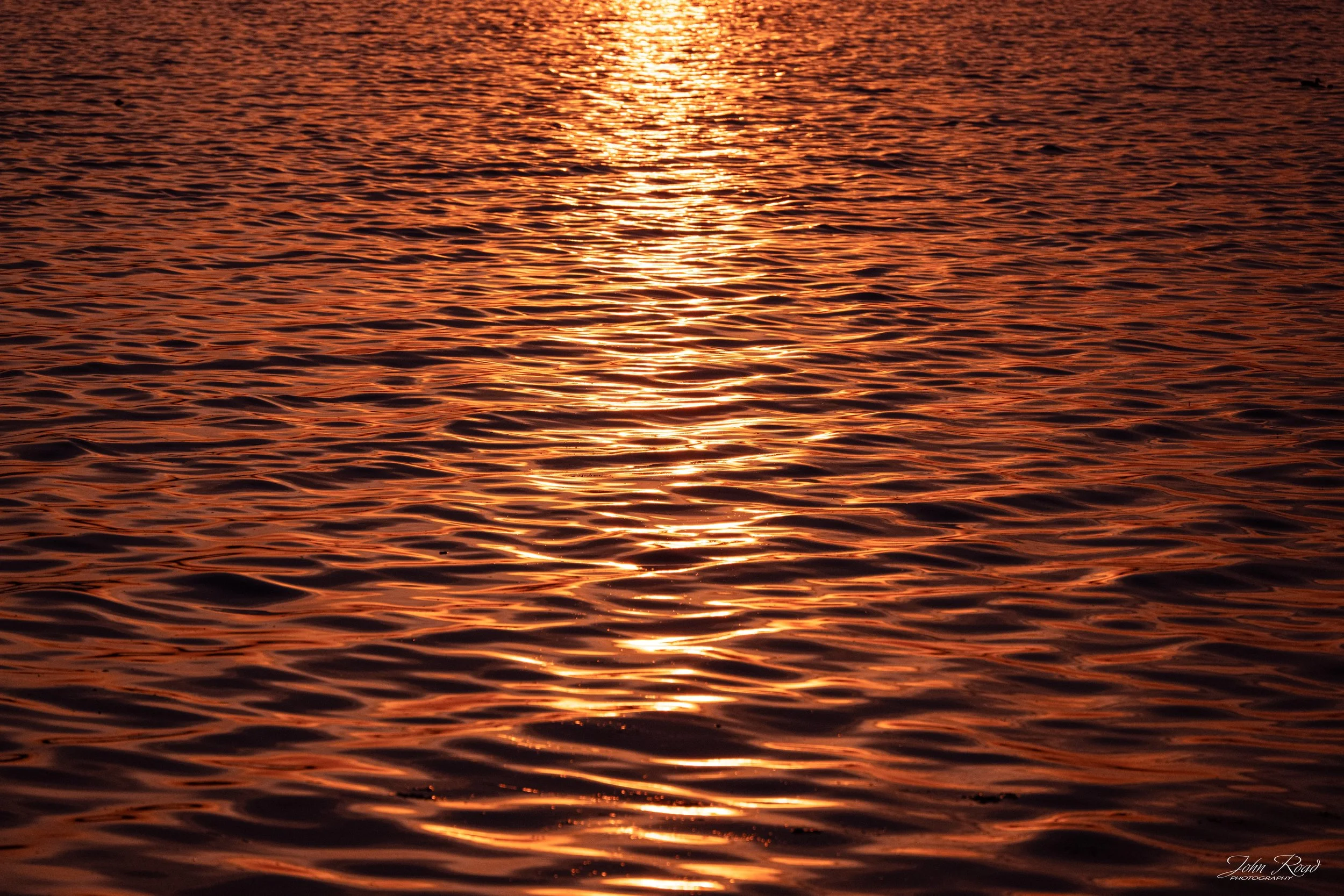 Golden sunlight creating abstract reflections and ripples across lake water