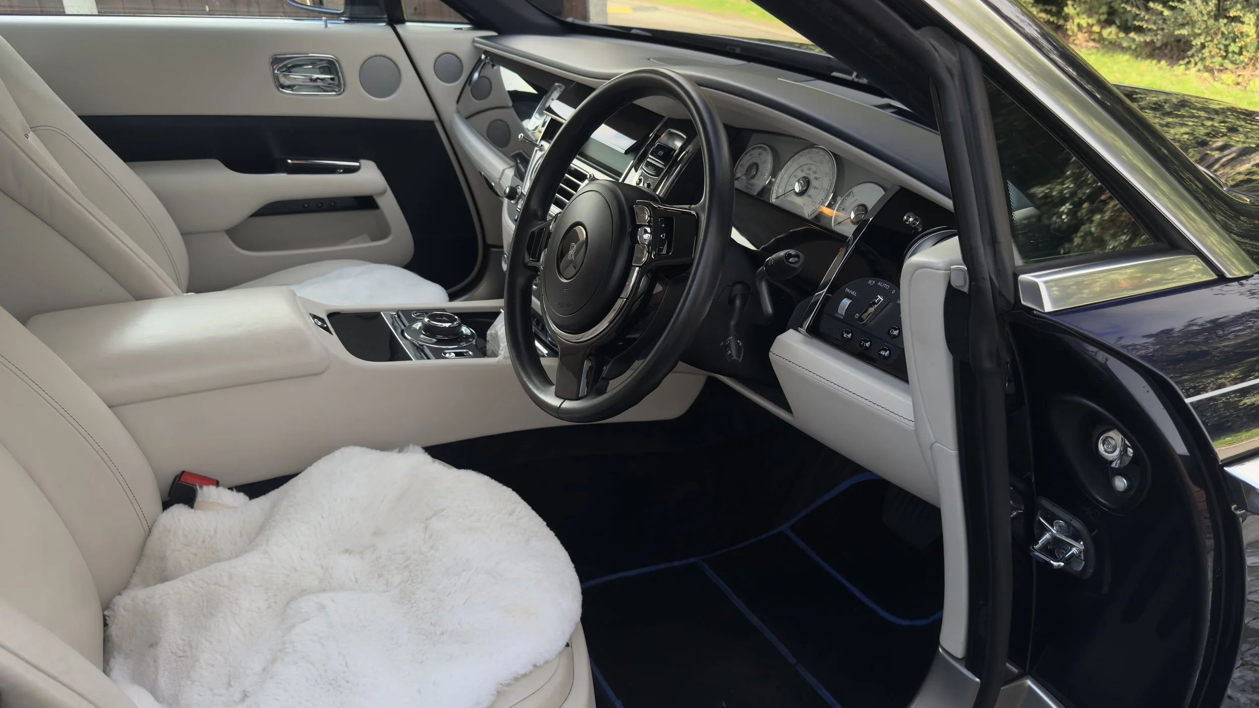 The interior of a luxury car with beige leather seats, a black steering wheel, and a modern dashboard with digital displays.