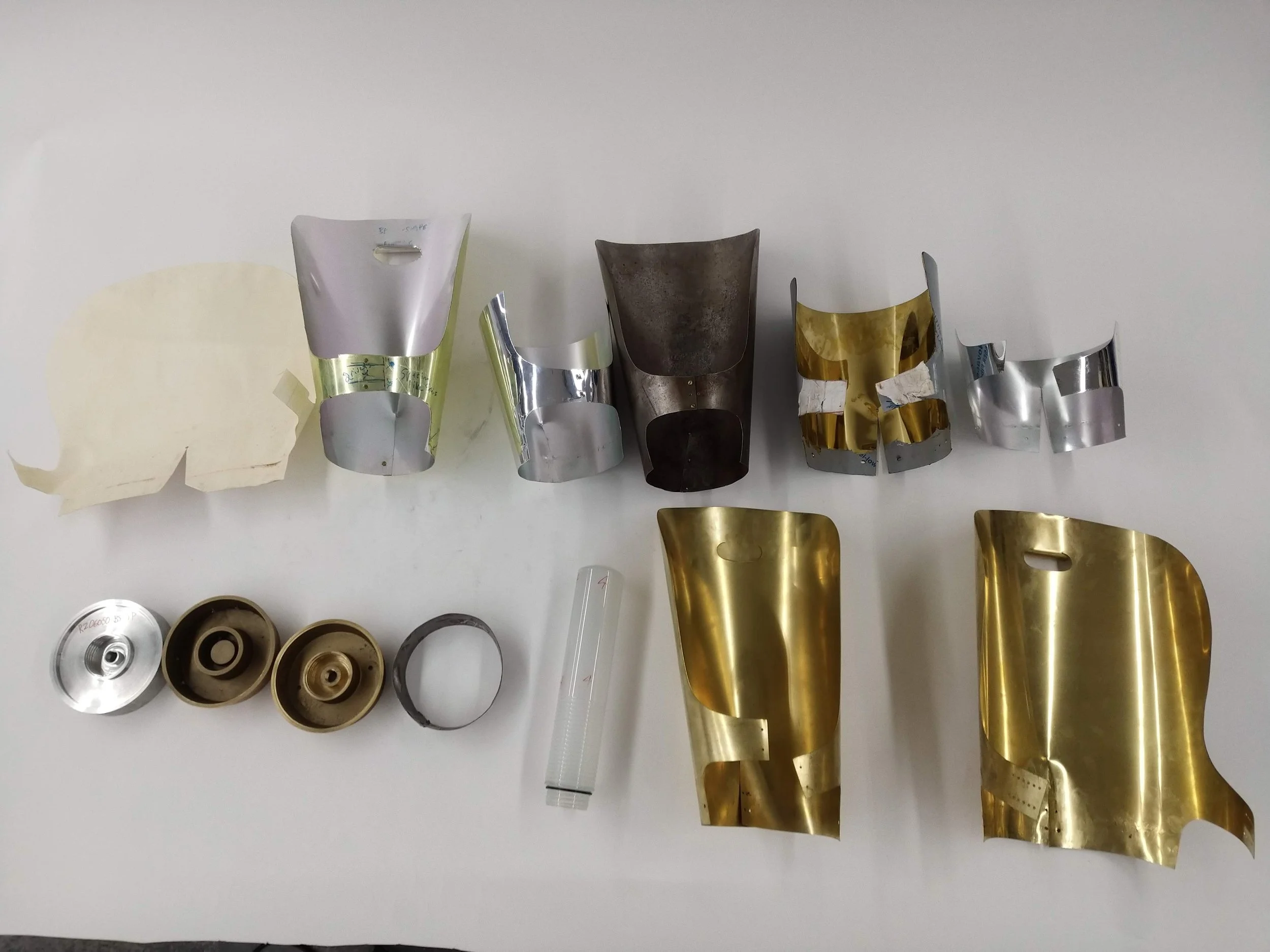 Prototyping process: paper, aluminum, and brass Sheet Metal Shades; paper, aluminum, and brass Bases; sample Glass; Brass Sheet Metal Shade with extra rivet holes for testing