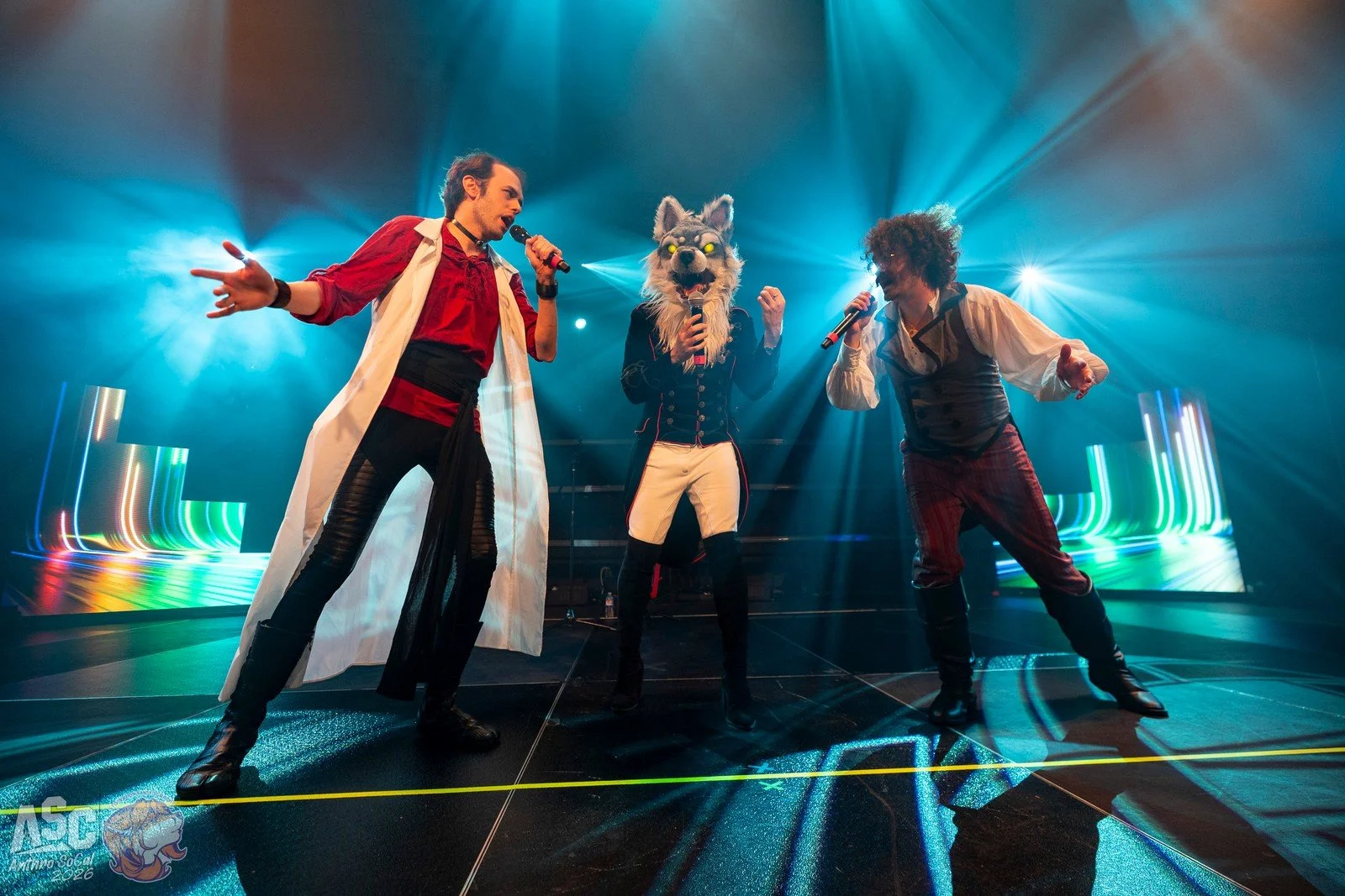 Pom, Chrono, and Charlie on stage, singing into microphones with colorful stage lights in the background.