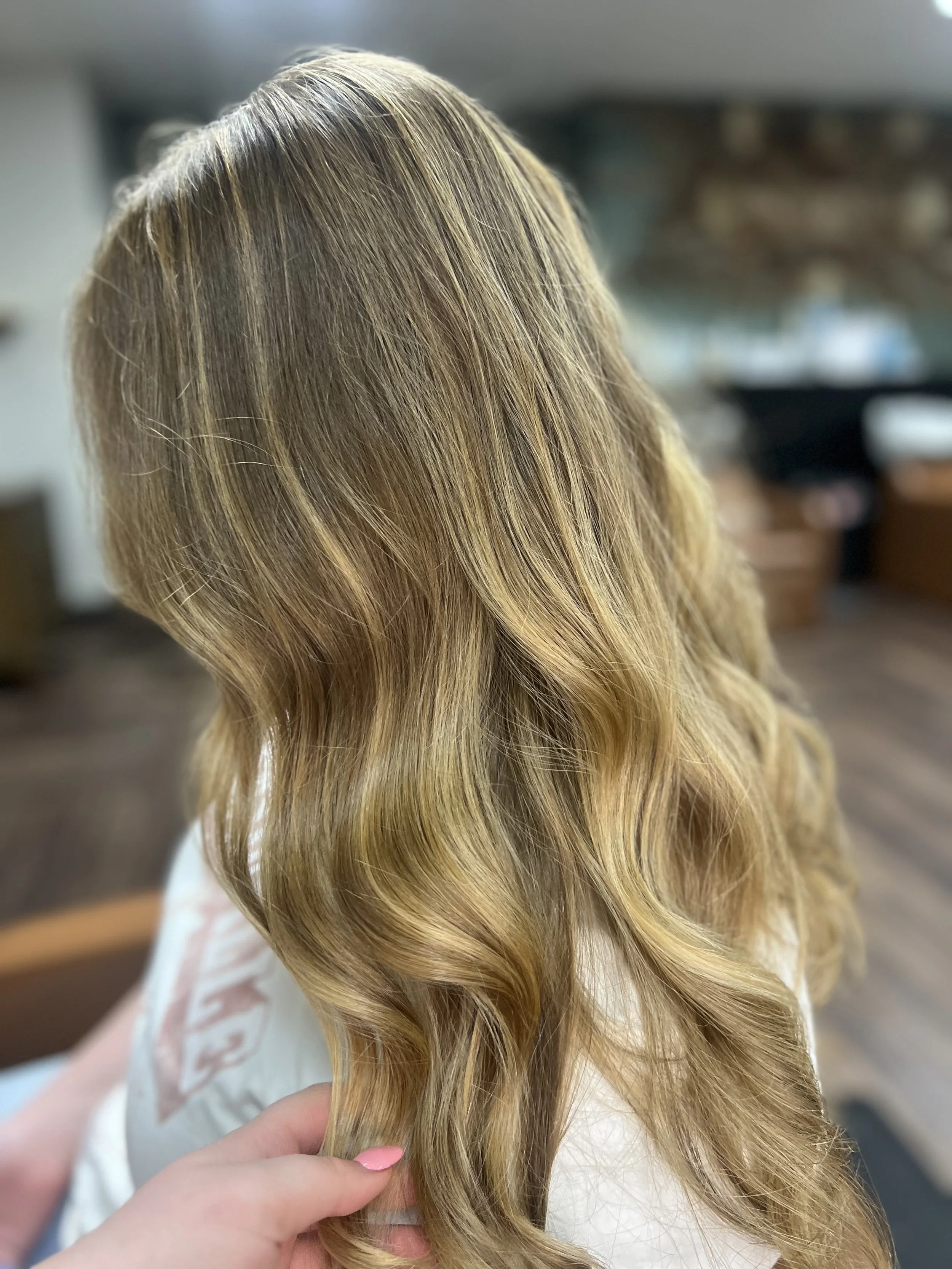 Close-up of a woman's long, wavy blonde hair with highlights.