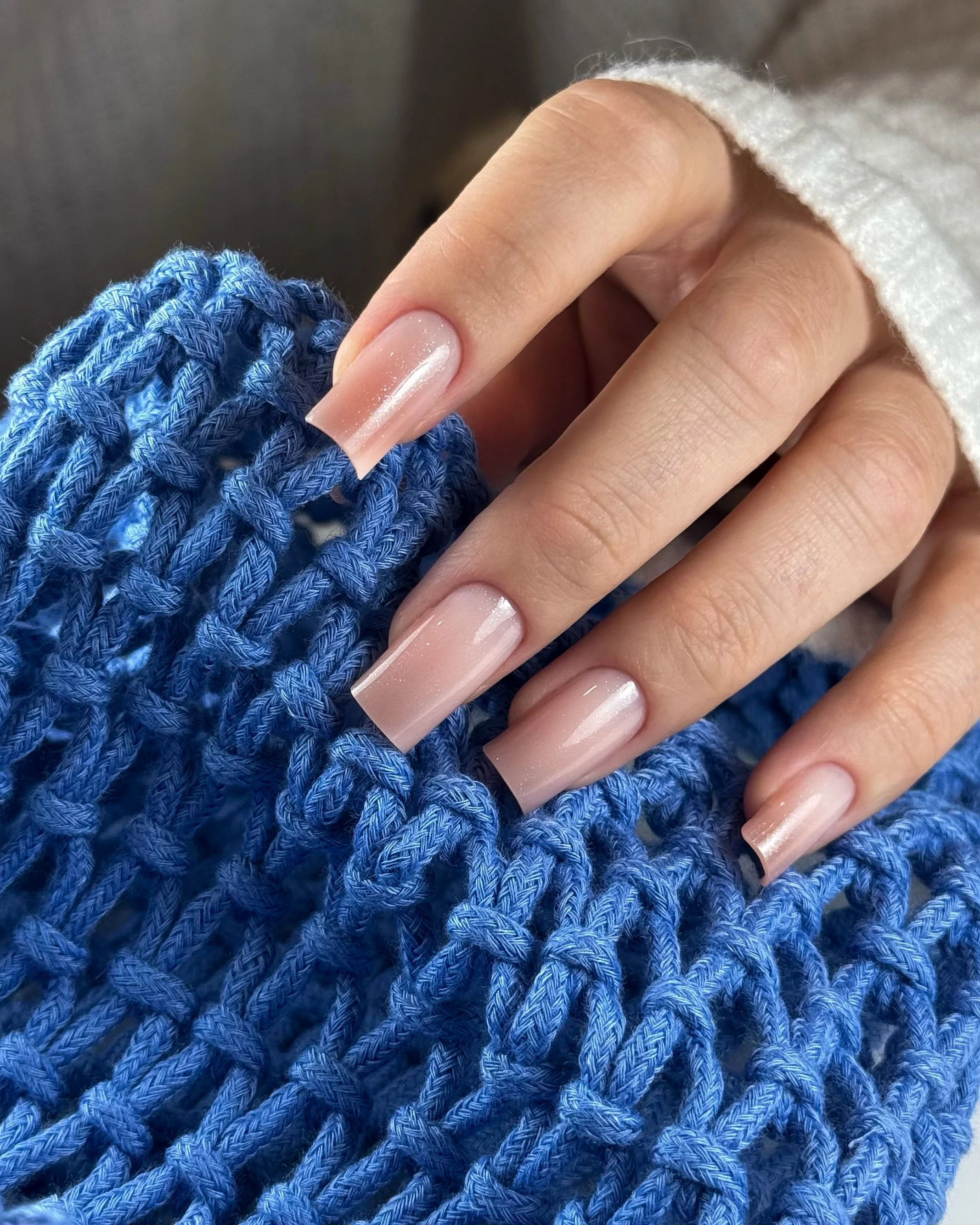 Close-up of a hand with manicured nails resting on a blue woven surface.