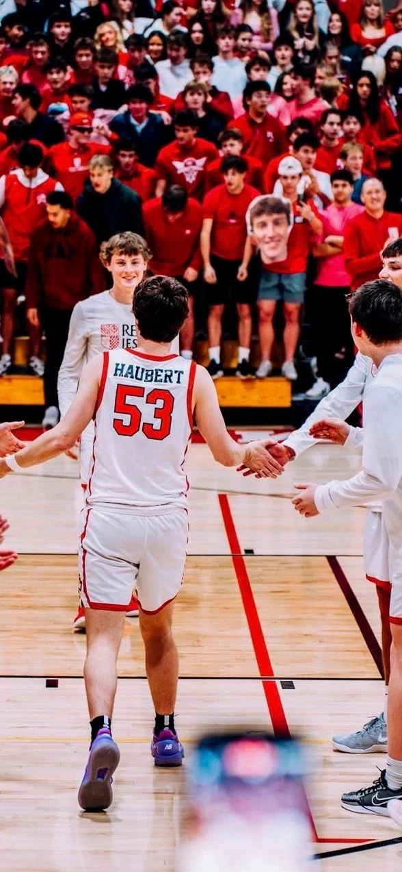 Joseph Haubert (#53) for Regis Jesuit runs through a gauntlet of teammates and befor the Red Sea at a home game.