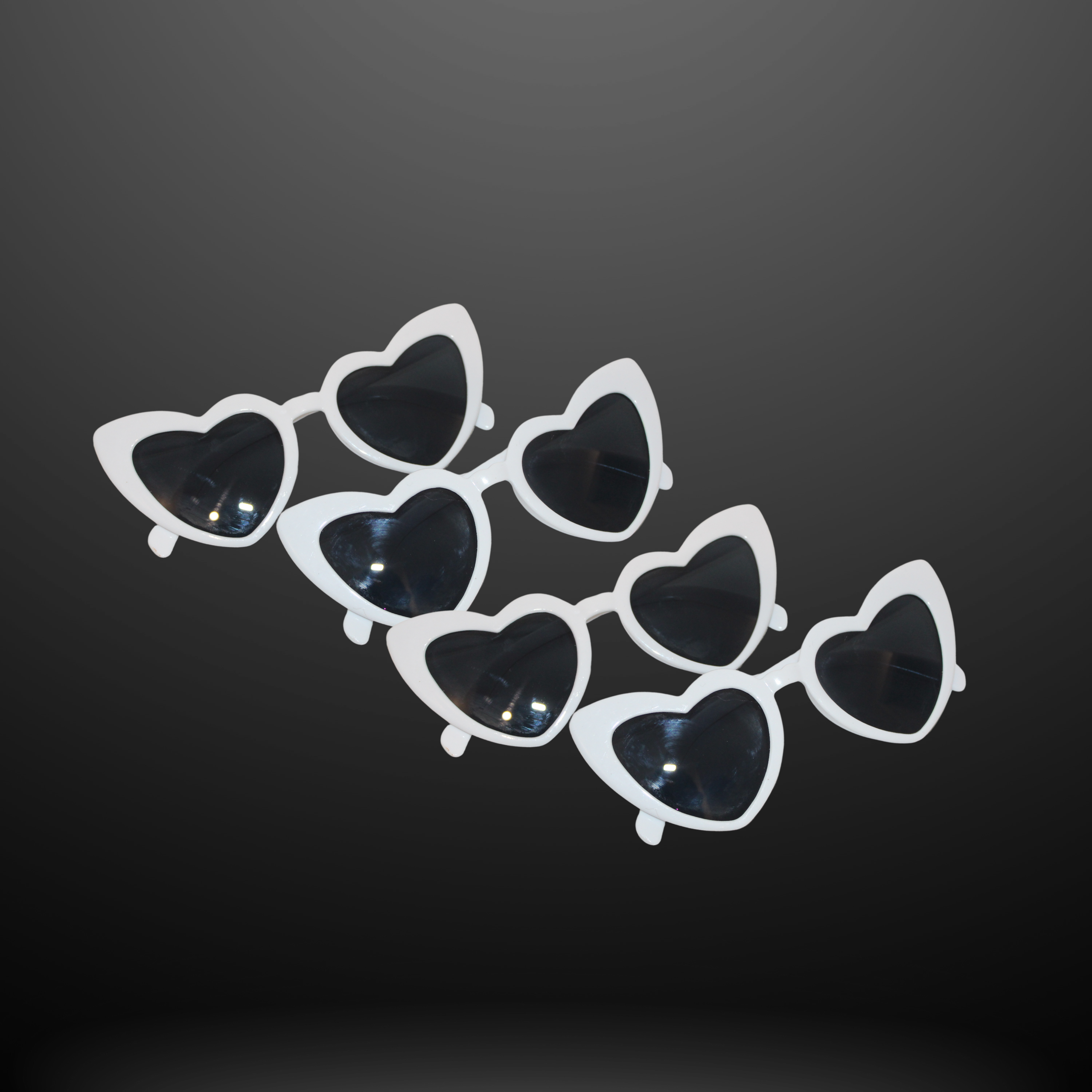 A pair of white sunglasses with heart-shaped black lenses, arranged in two overlapping rows on a dark gradient background.